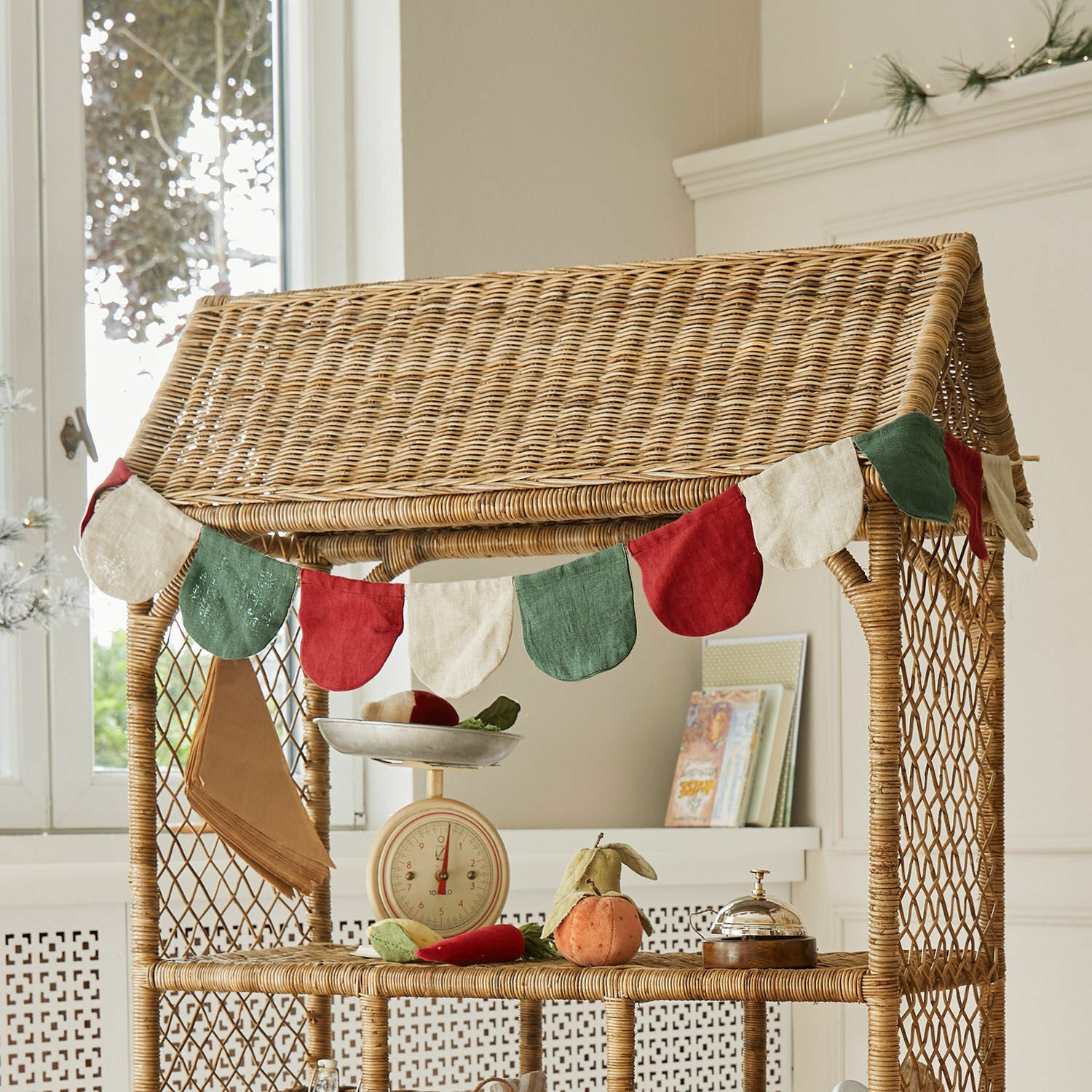 Guirlande de fanions Eirun Guirlande décorative en tissu rouge, vert et crème sur étagère en osier pour décoration intérieure
