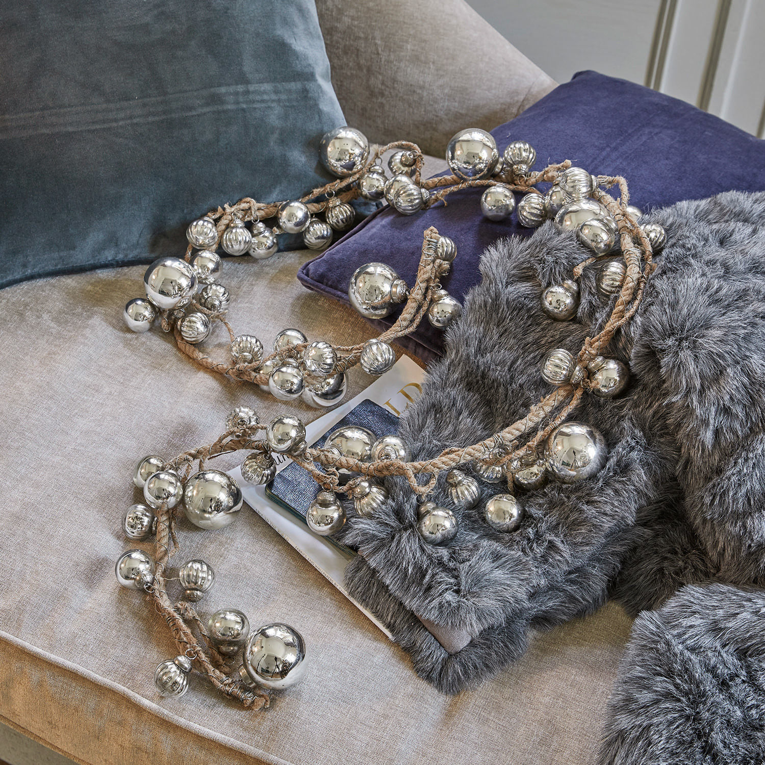 Guirlande Pearls Guirlande décorative avec boules métalliques argentées sur corde en lin posée sur canapé avec coussins