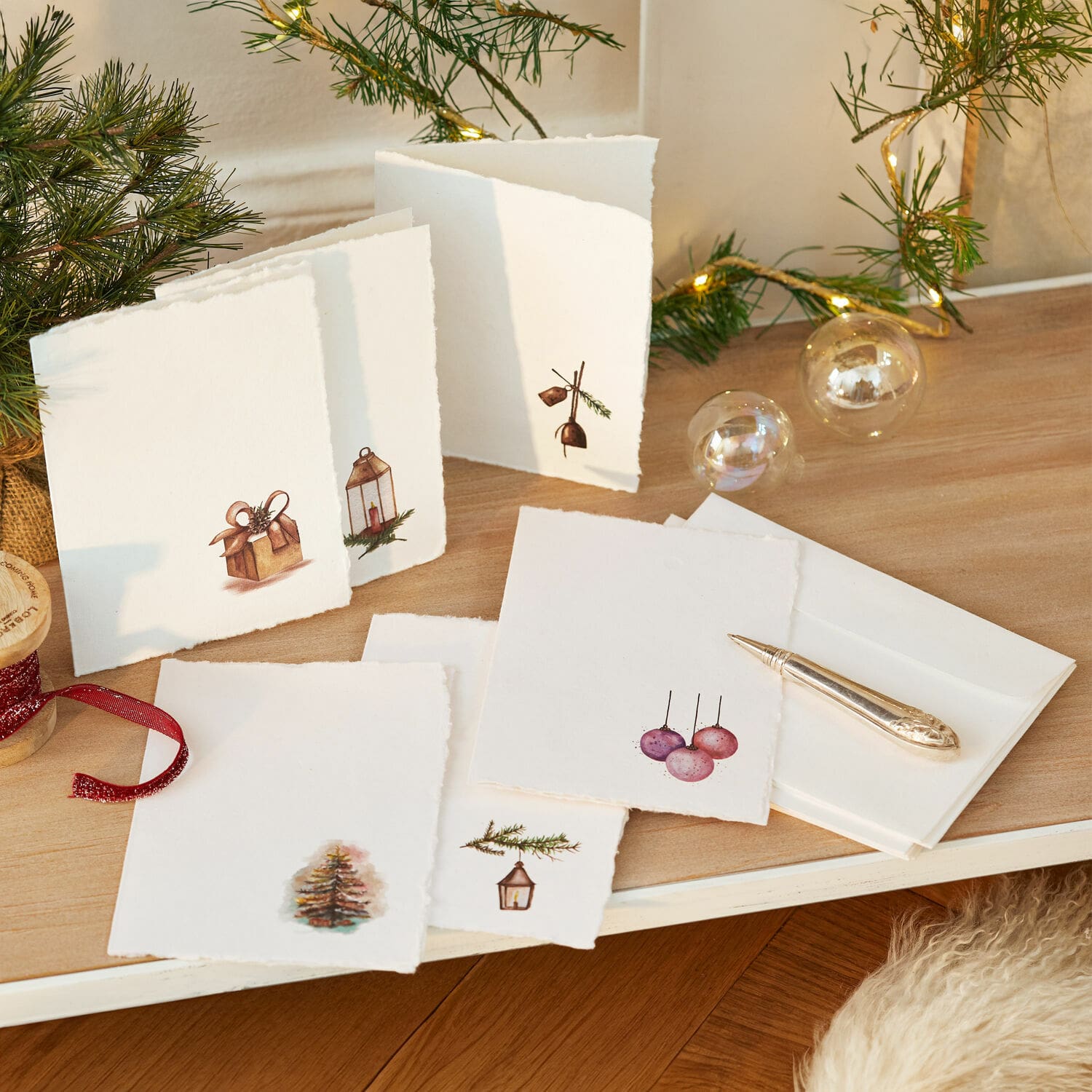 Lot de 6 cartes de vœux Aeloria Ensemble de cartes de vœux blanches avec motifs de sapin et cadeaux sur table en bois avec guirlande lumineuse