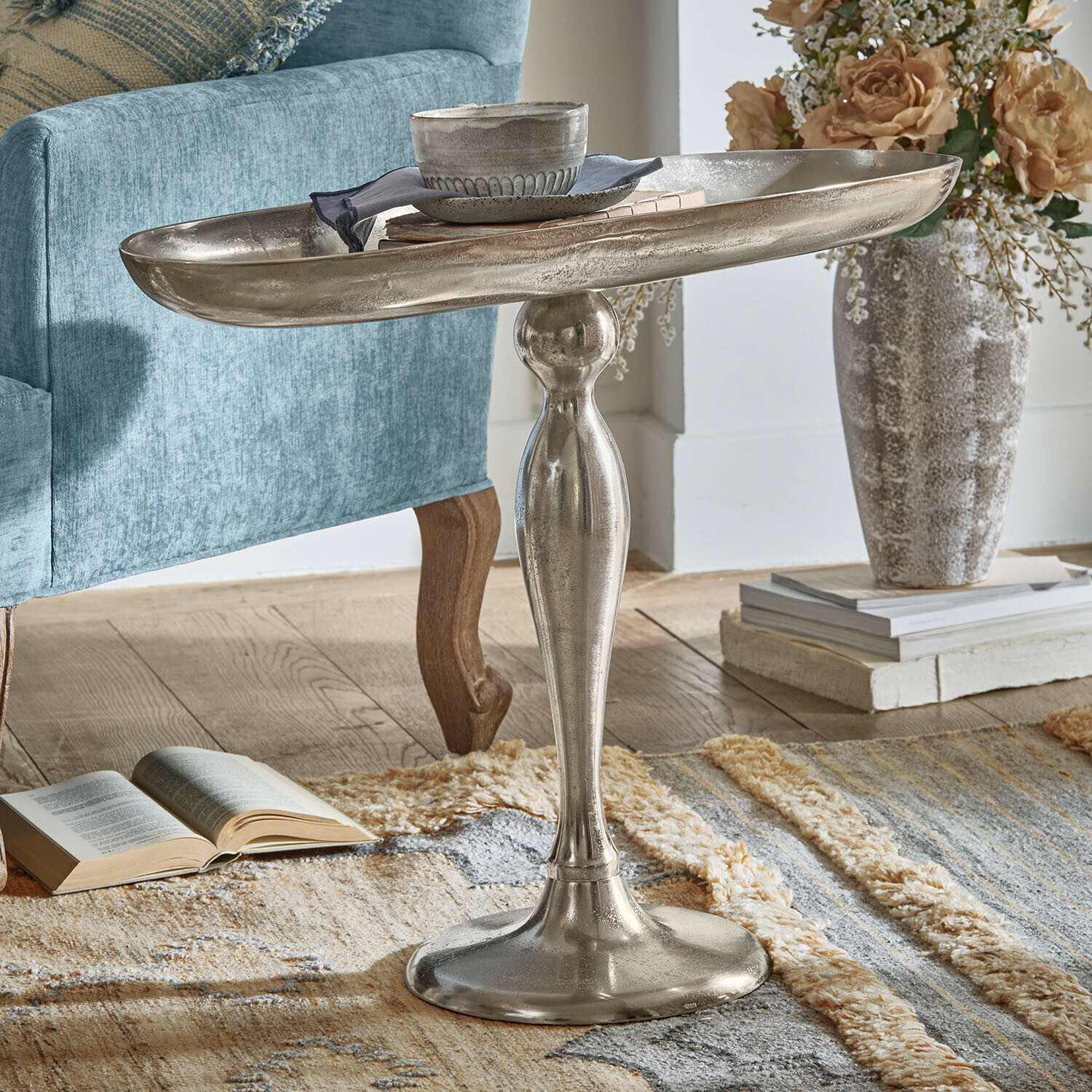Bijzettafel Stonebrook Zilverkleurige metalen bijzettafel met decoratieve voet op tapijt naast blauwe fauteuil