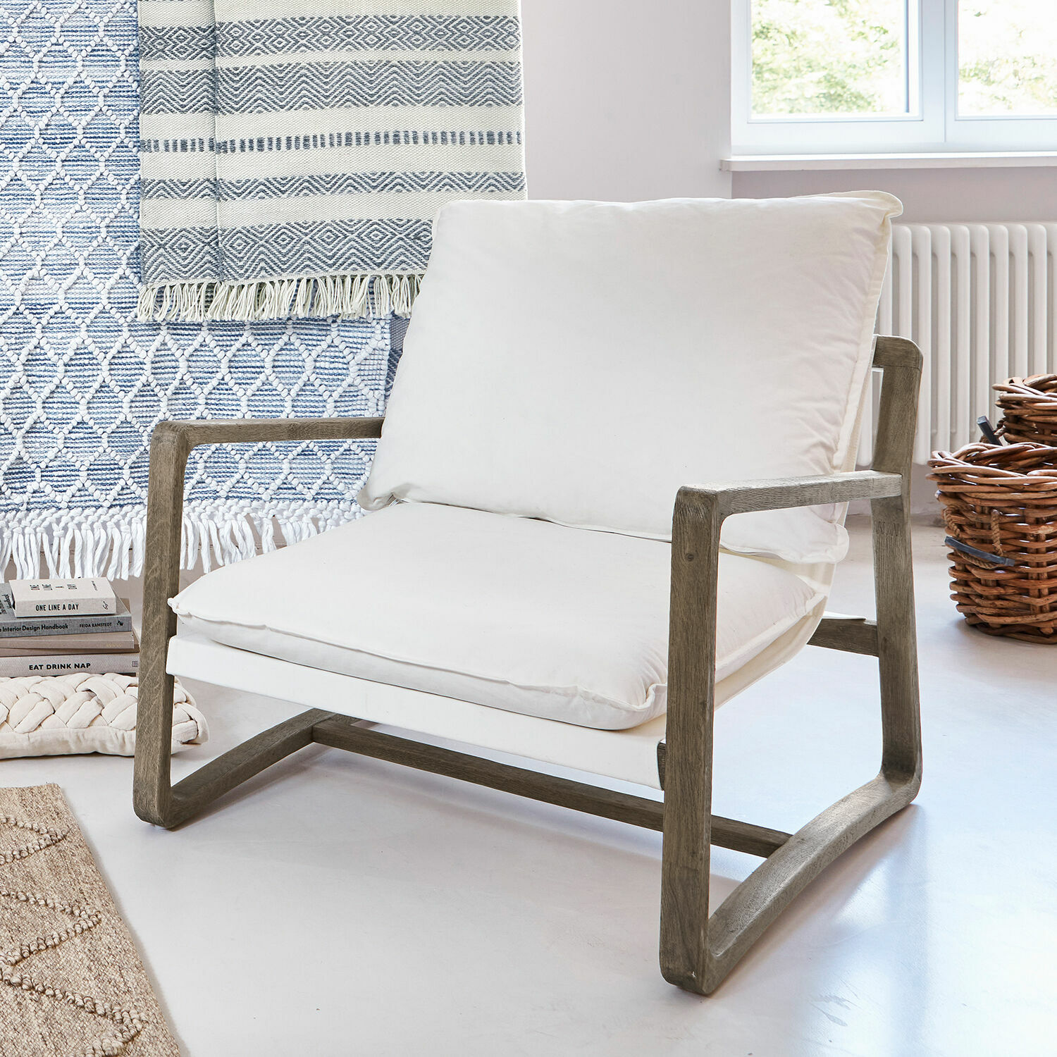 Fauteuil avec cadre en bois et coussin en coton blanc dans un intérieur lumineux et moderne