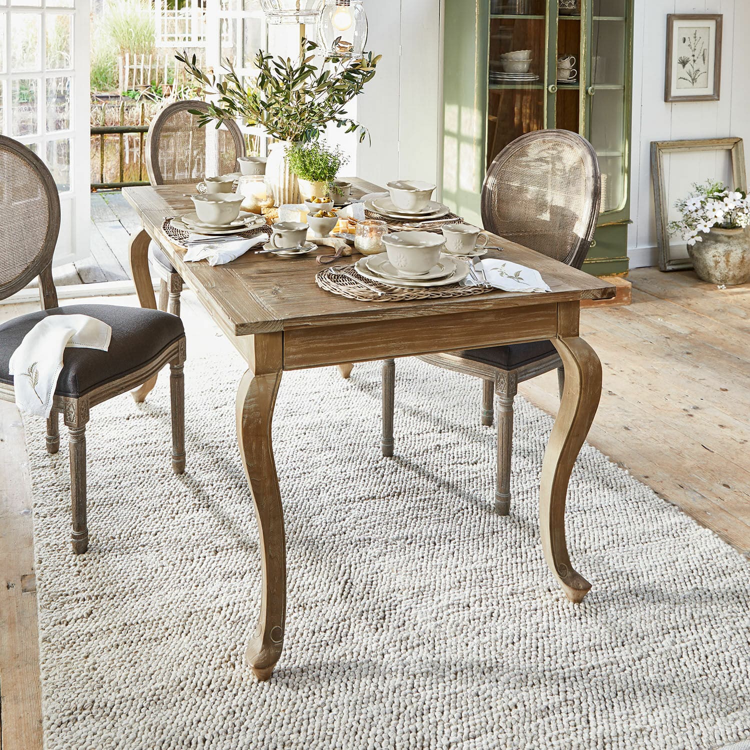 Table Plaish Table à manger en bois rustique avec pieds sculptés et vaisselle claire dans une salle lumineuse