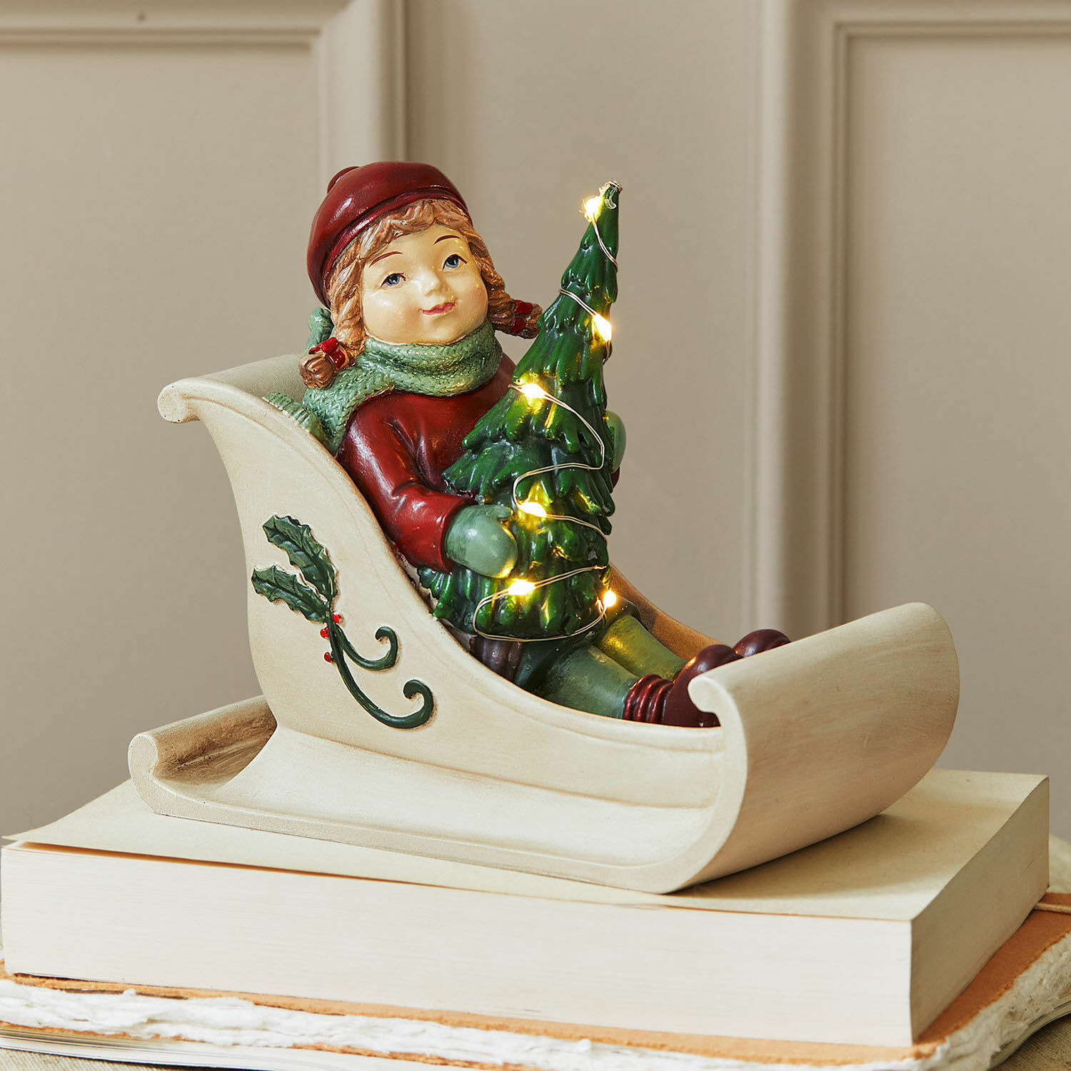 Ledfiguurtje Soriala Beeldje van kind in slee met groene kerstboom en lichtjes, kerstdecoratie op boeken