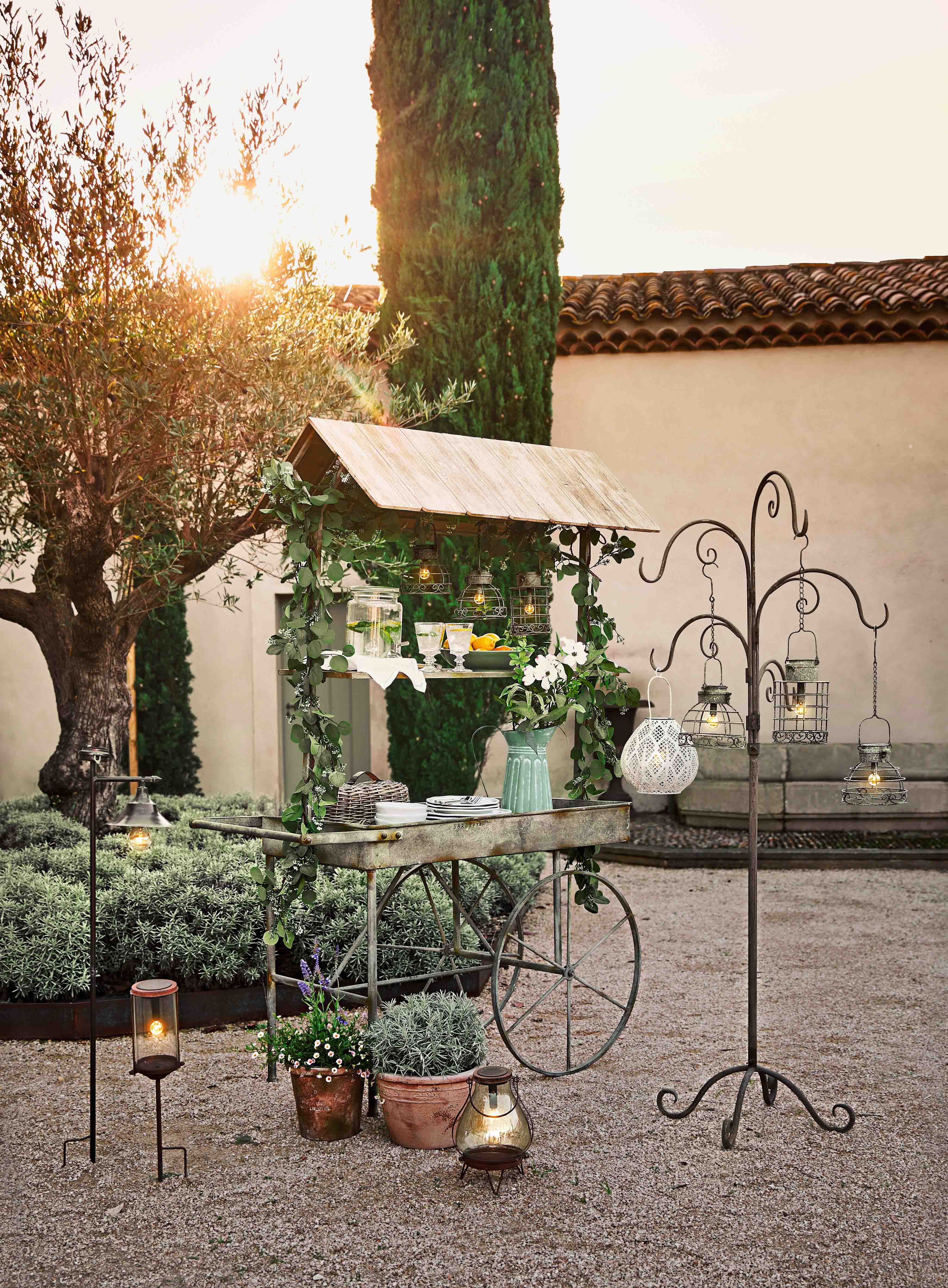 Chariot de jardin en métal avec toit en bois, décorations végétales et lanternes suspendues en extérieur