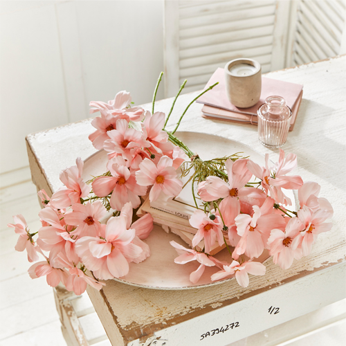 Delicate roze decoratieve bloemen op witte houten schaal op rustieke tafel, interieurdecoratie