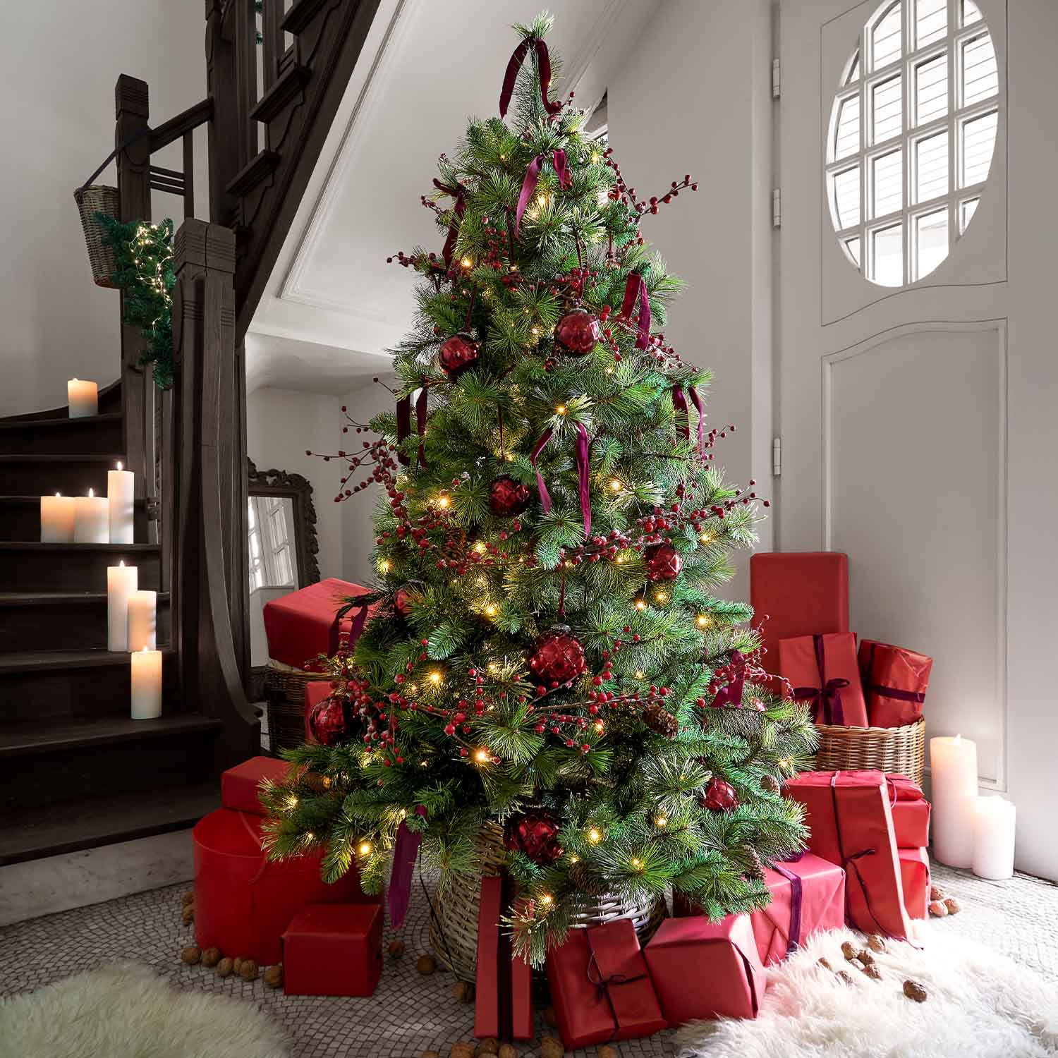 Sapin de Noël décoré de branches vertes, boules rouges et cadeaux emballés en rouge au pied