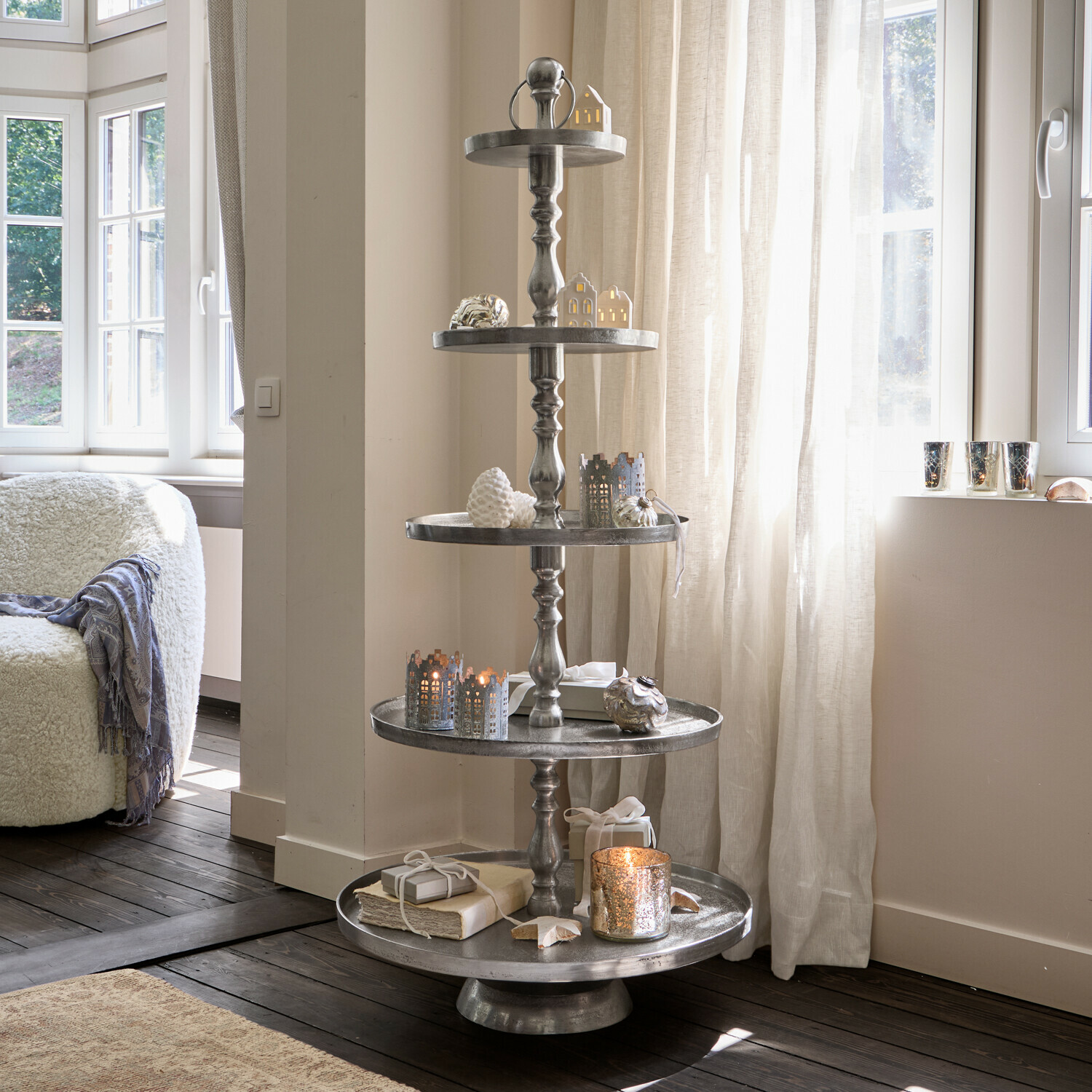 Etagère Magonie Vijflaagse metalen kerstdecoratie met groene takken en gouden ballen in woonkamer
