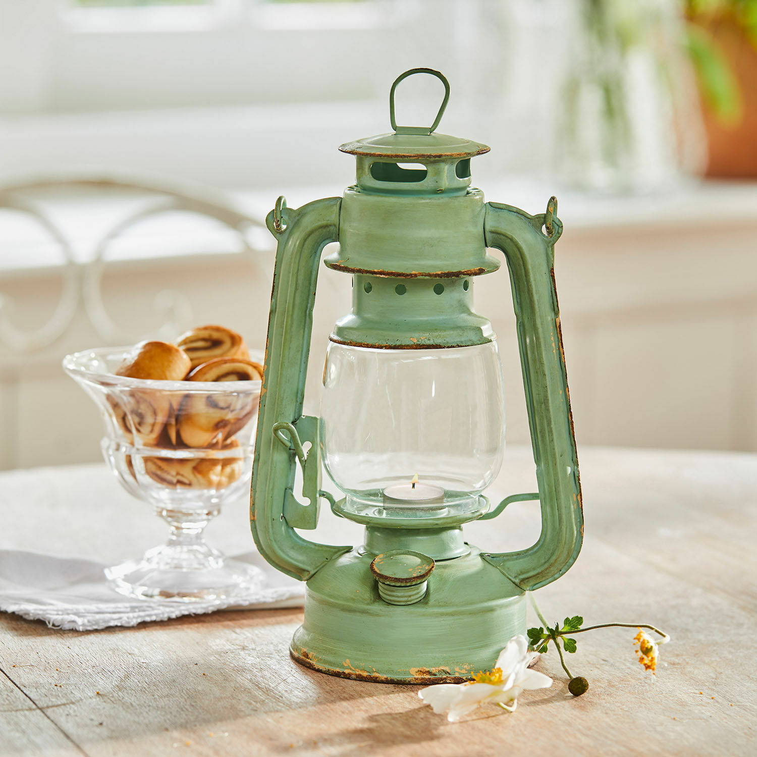 Groene metalen lantaarn met verouderd effect op houten tafel, gebak op de achtergrond