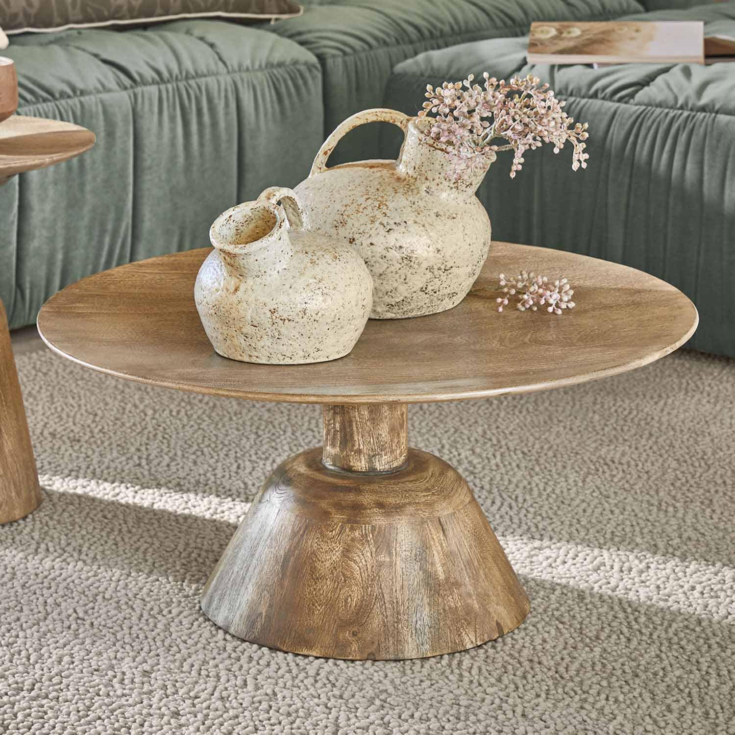 Table basse en bois avec deux vases en céramique crème à effet vieilli sur un tapis beige