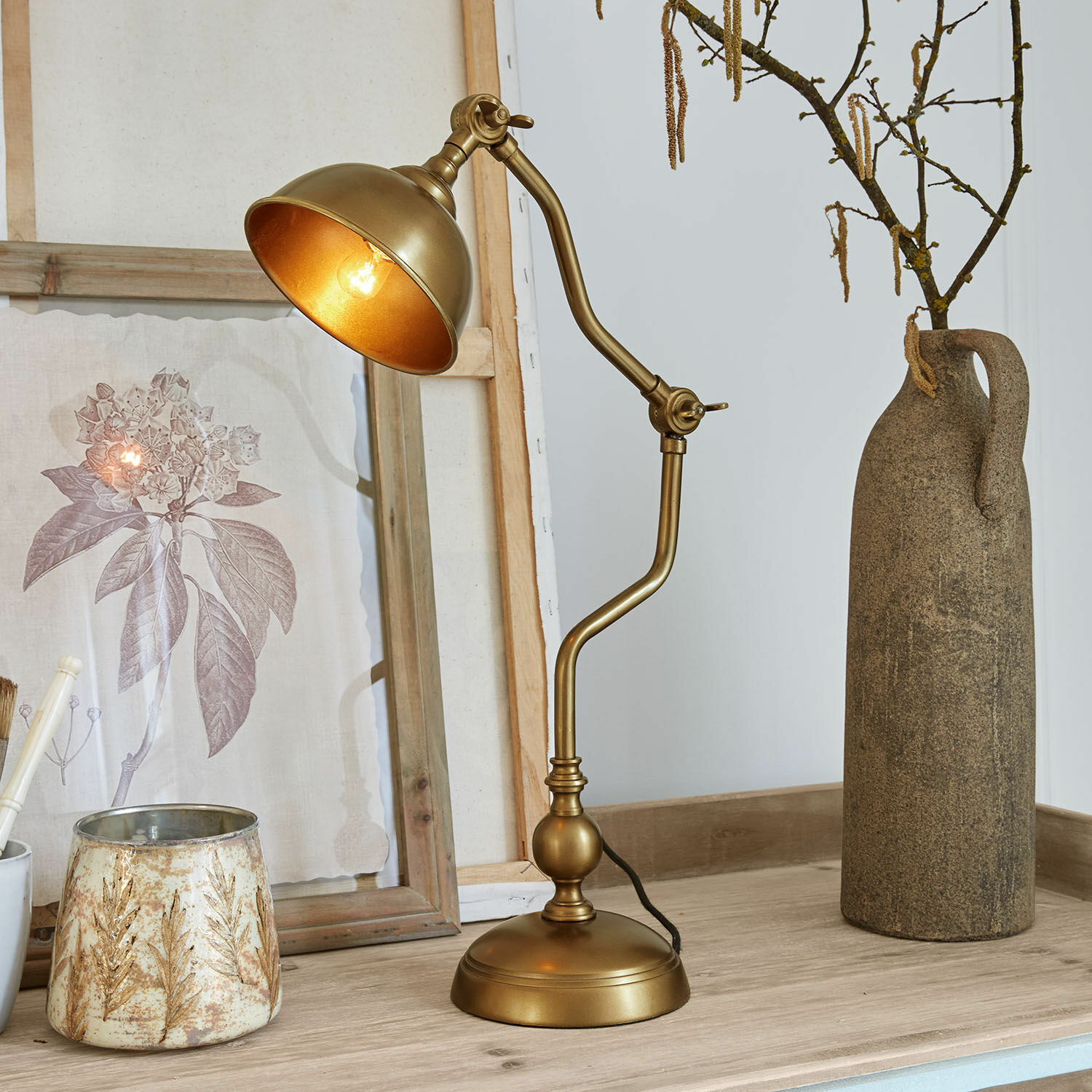 Lampe à poser Harrowden Lampe de table en métal doré avec bras réglable sur une table en bois avec décorations