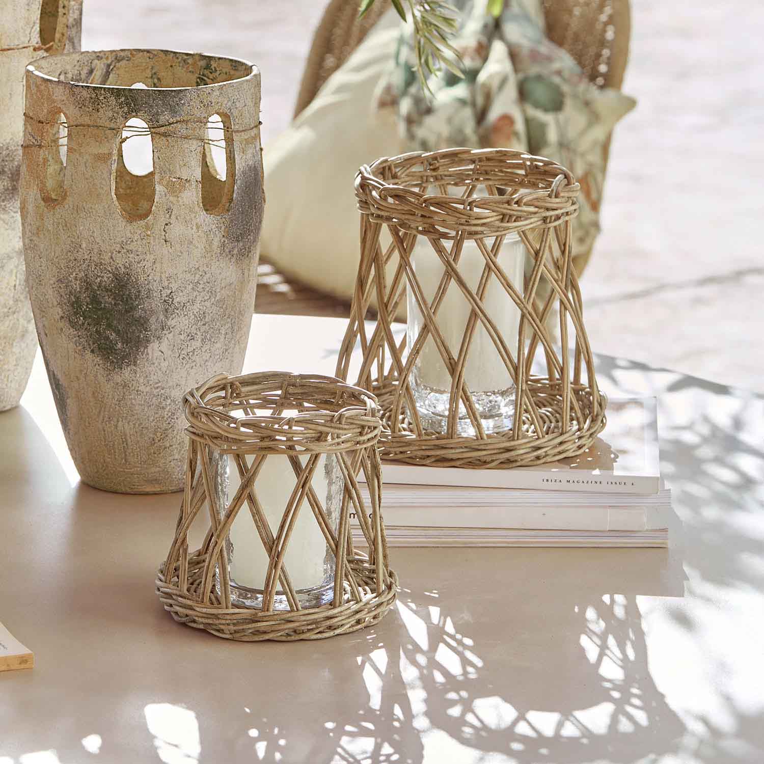 Twee windlichten van natuurlijk riet met witte kaarsen op lichte tafel, interieurdecoratie