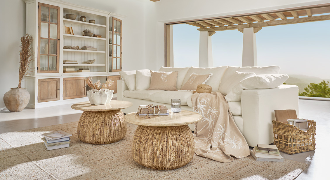 Salon lumineux avec canapé blanc, tables basses en osier et bois naturel dans un style bohème