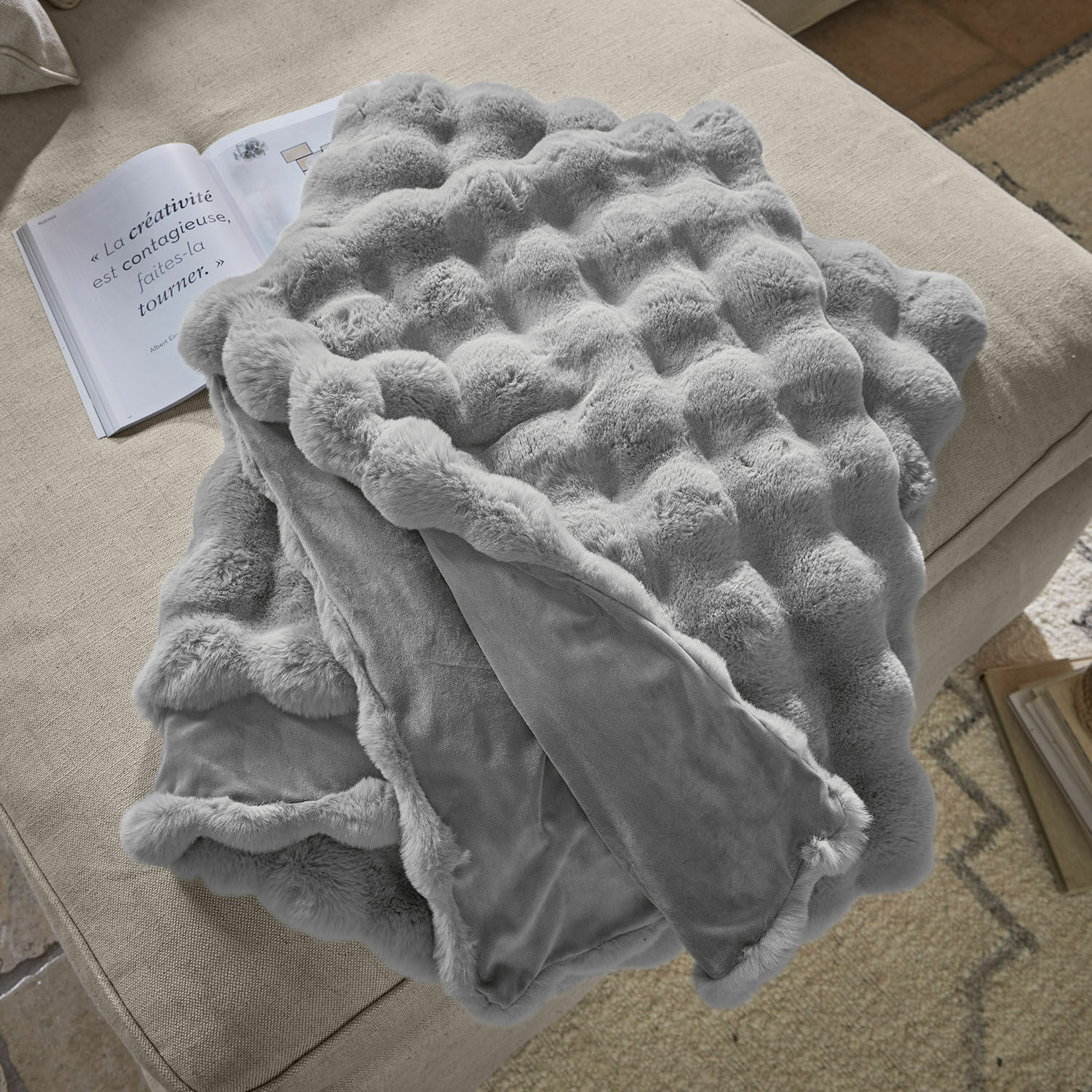 Plaid Zalina Zachte grijze deken met bontpatroon op beige bank, perfect voor decoratie en warmte in huis