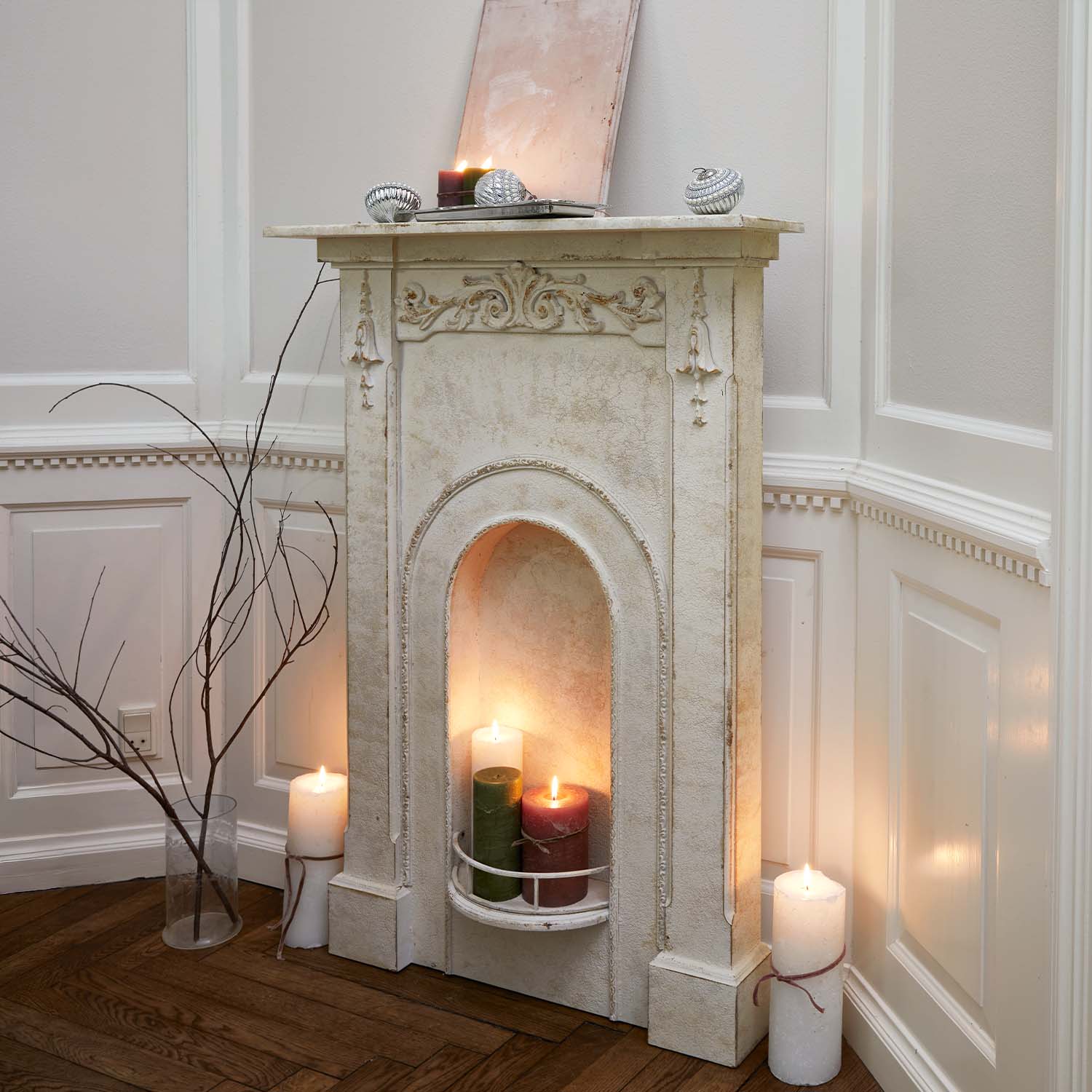 Decoratieve witte schoorsteen met sierlijke reliëfs en brandende kaarsen in rustieke kamer