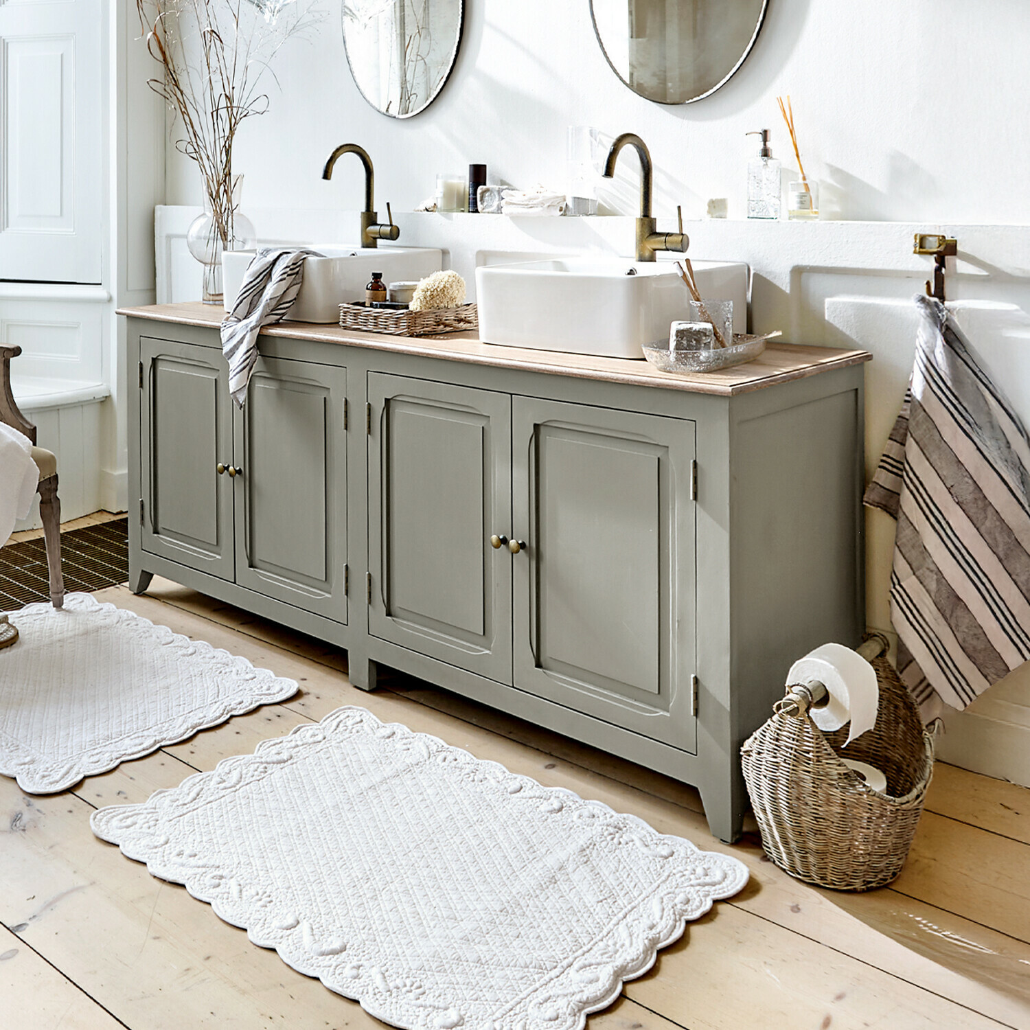 Meuble à double-vasque Bastanès Meuble de salle de bain gris en bois avec double vasque et miroirs ronds dans une salle lumineuse