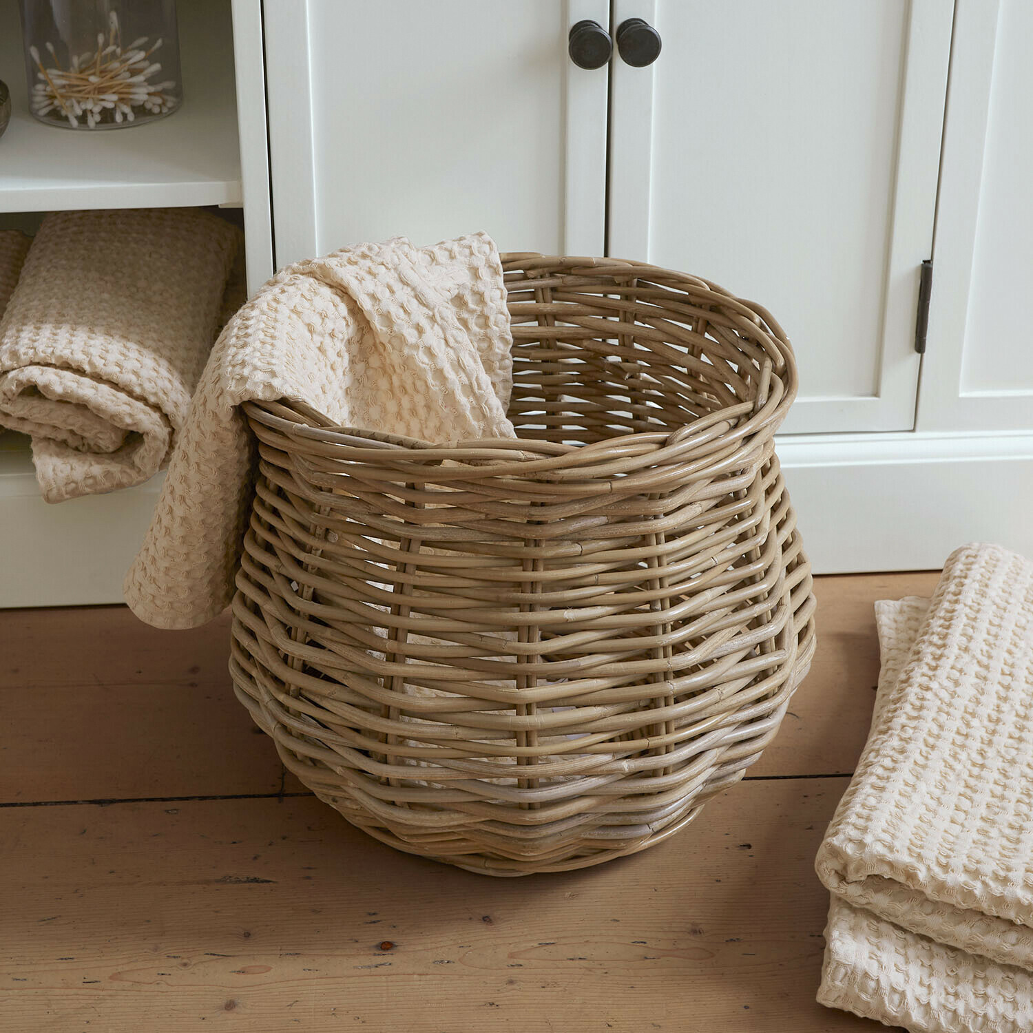 Mand Elvendia Natuurlijke rieten mand met crèmekleurige wafelhanddoek op lichte houten vloer