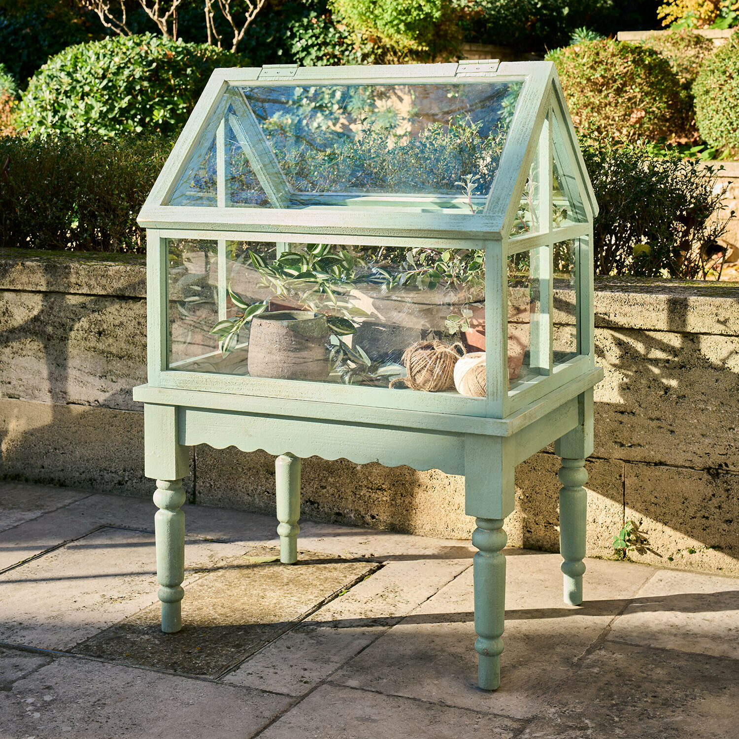 Plantenkas Isoméline Kleine groene houten kas op poten met planten en garenrollen voor de tuin