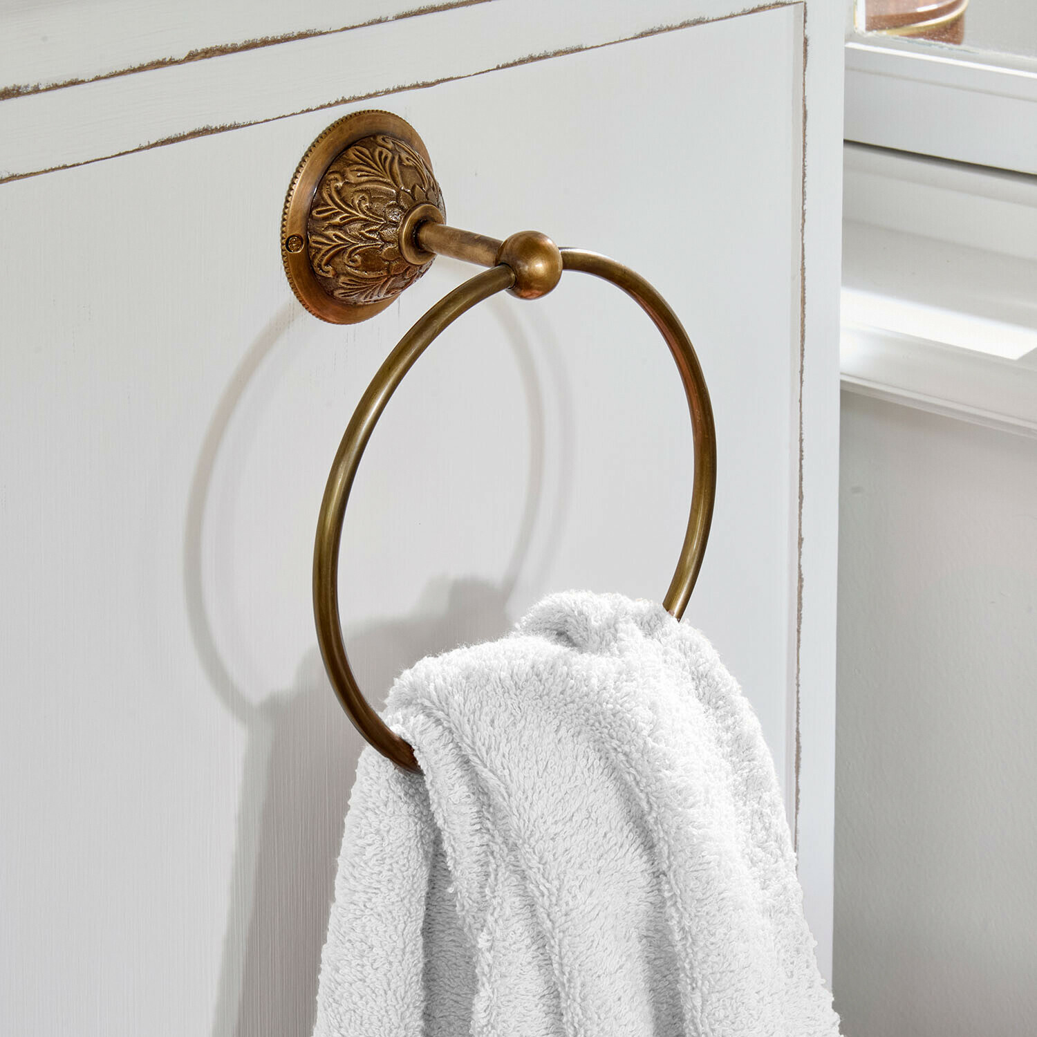 Handdoekhouder Quenlivre Ronde handdoekring van messing met decoratieve bevestiging aan witte badkamerdeur