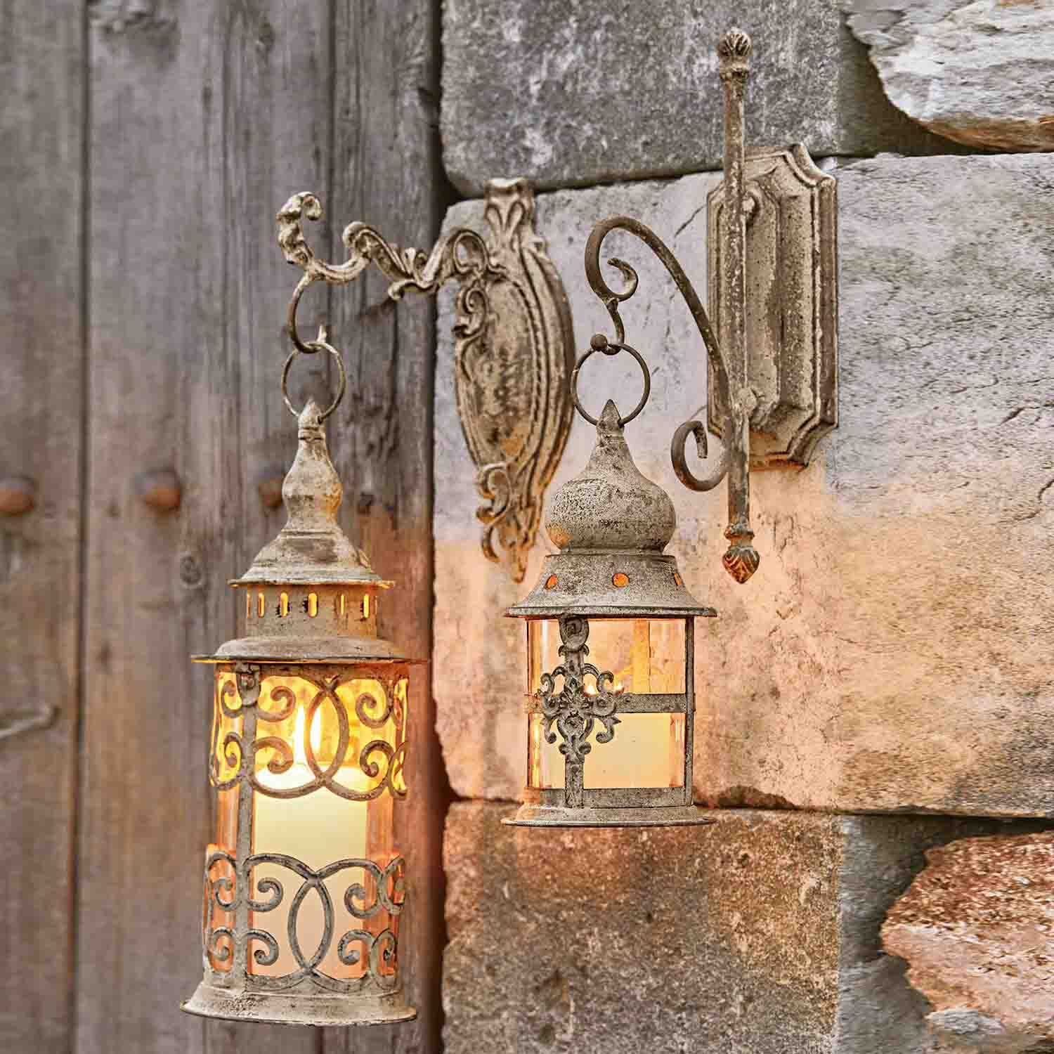Twee rustieke metalen wandlampen in verweerde beige kleur die een stenen muur verlichten
