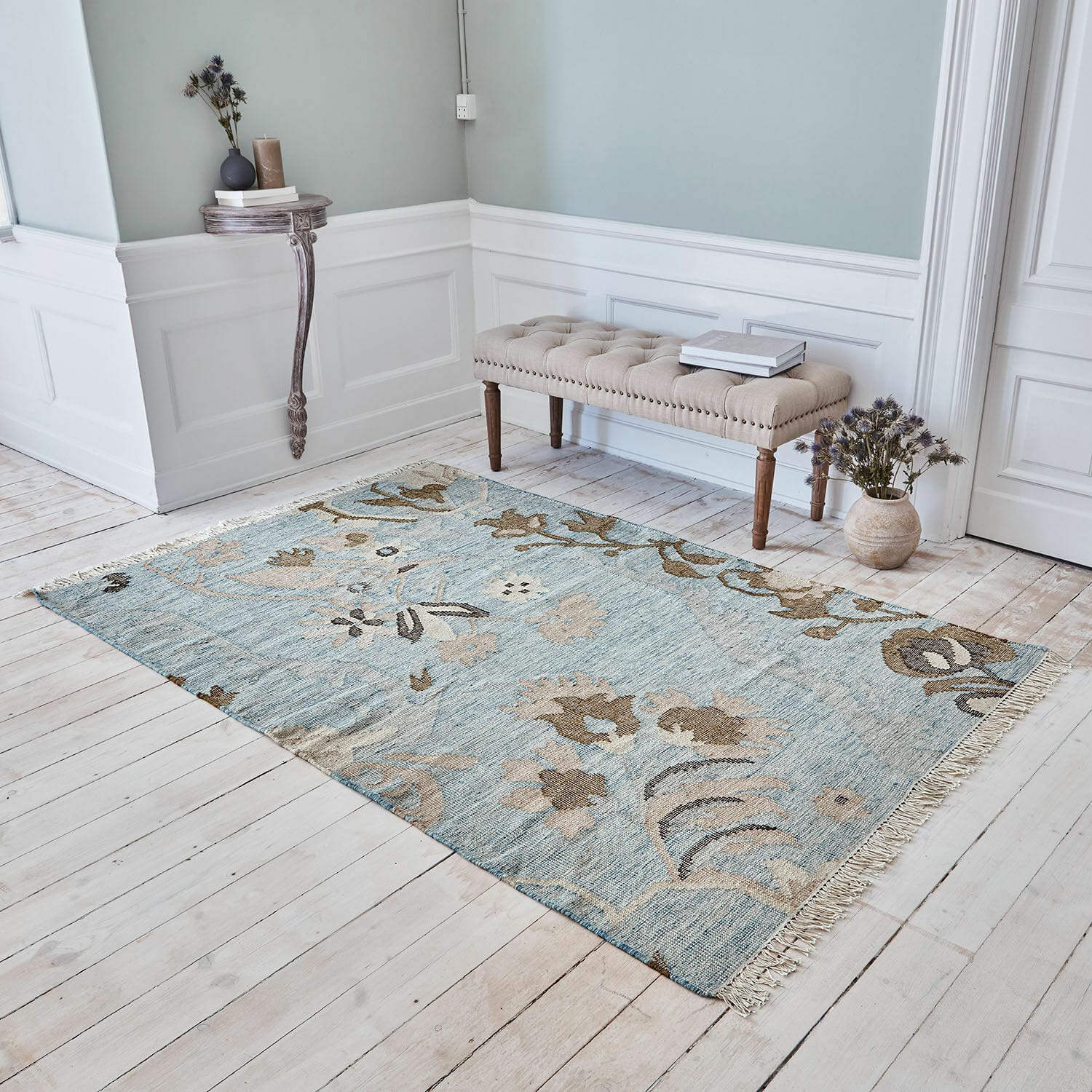 Tapis Nére Tapis en coton bleu clair avec motifs floraux beige dans une pièce au sol en bois clair