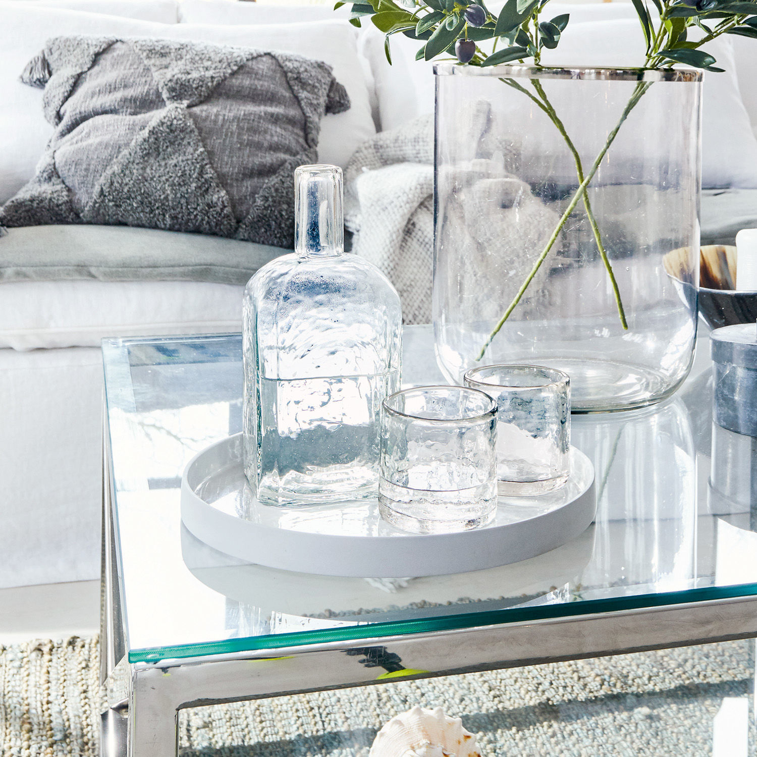 Ensemble en verre avec bouteille et deux verres sur un plateau blanc sur une table en verre