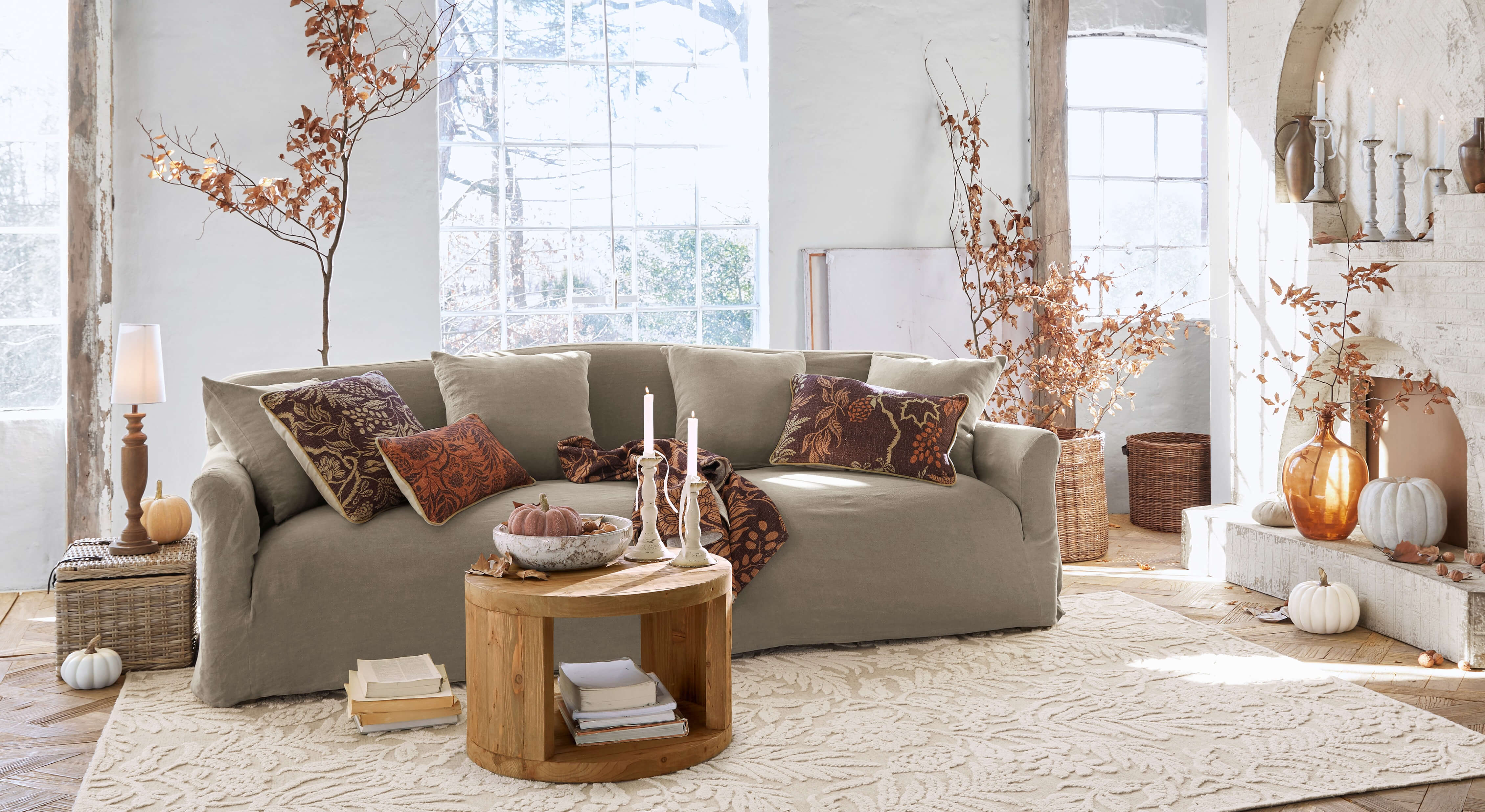 Beige stoffen bank in gezellige woonkamer met herfstdecoratie en houten salontafel