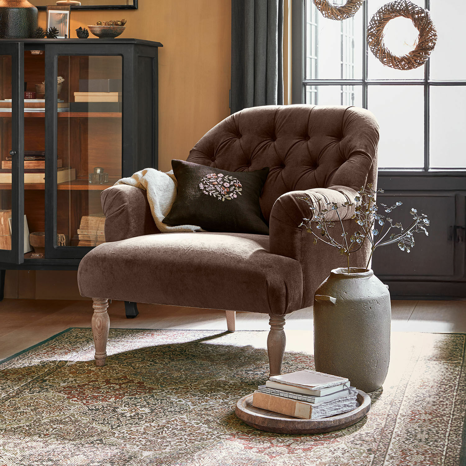 Fauteuil Shambrook Fauteuil en velours marron avec dossier capitonné et pieds en bois dans un salon chaleureux avec tapis