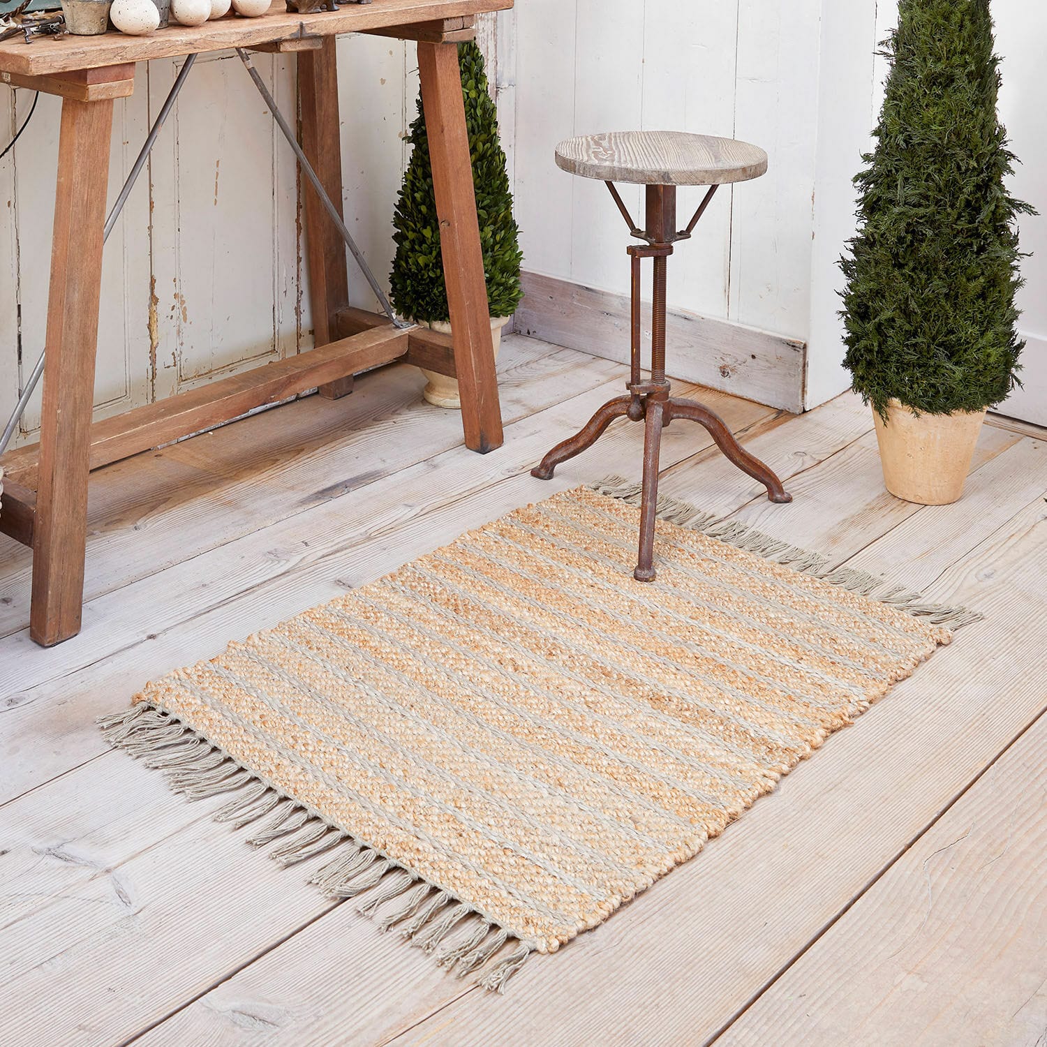 Vloerkleed Voyage Jute vloerkleed in beige-grijze strepen met franjes op lichte houten vloer, interieurdecoratie