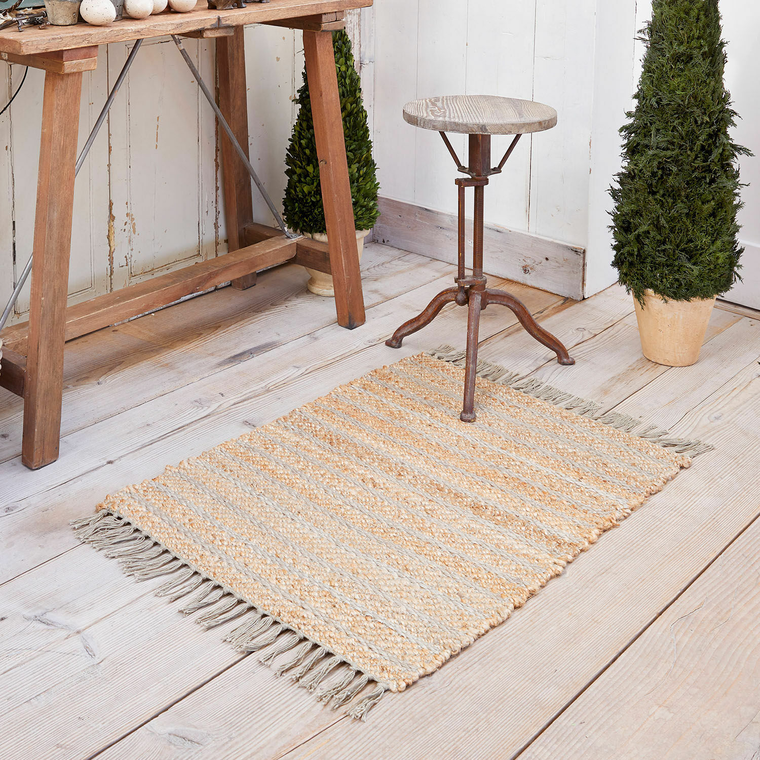 Vloerkleed Voyage Jute vloerkleed in beige-grijze strepen met franjes op lichte houten vloer, interieurdecoratie
