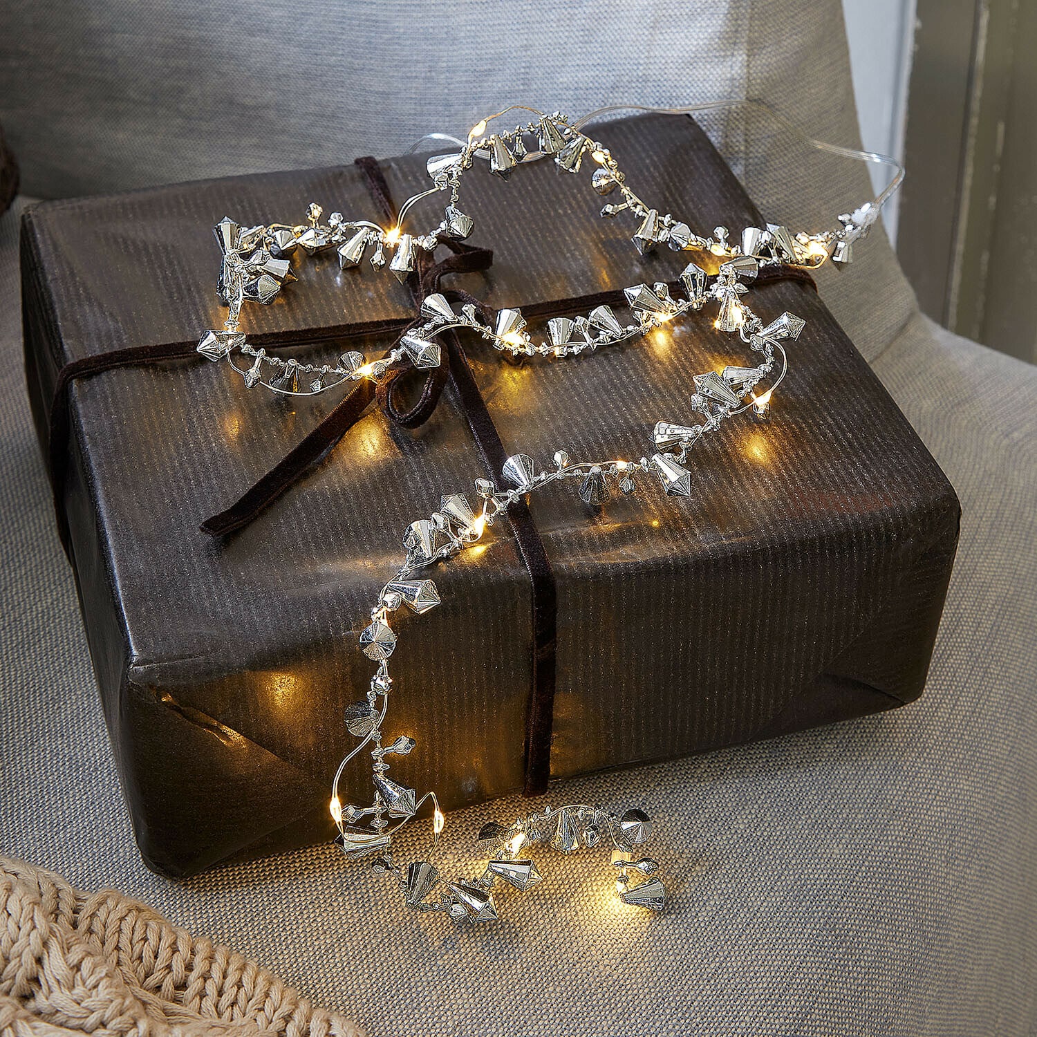 Lichtsnoer Bryesa Fijne lichtsnoer met zilverkleurige metalen versieringen op een donker cadeauverpakking
