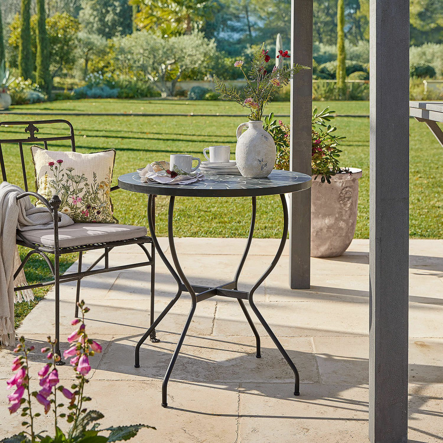 Tafel Ballaigues Ronde tuintafel met metalen frame en grijs mozaïekblad op zonnig terras