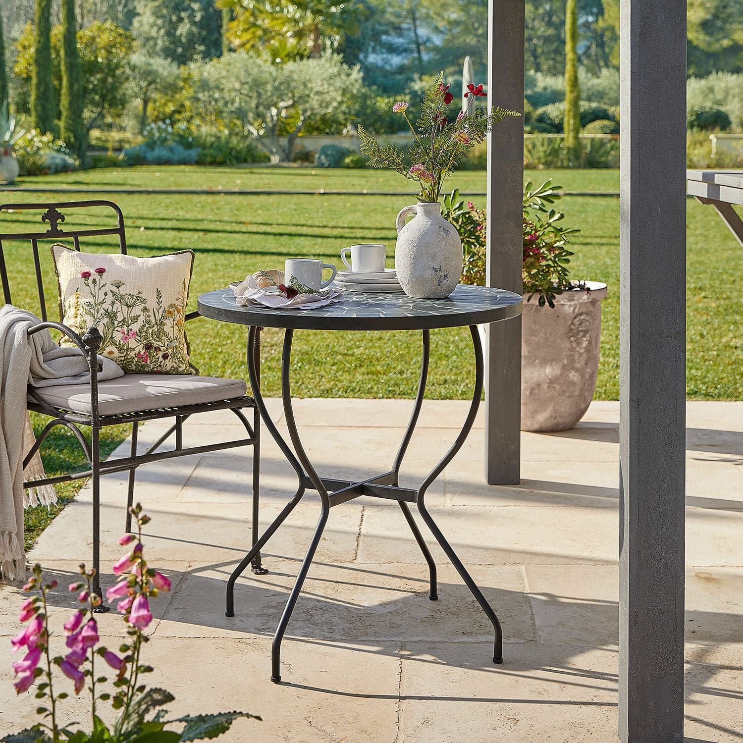 Tafel Ballaigues Ronde tuintafel met metalen frame en grijs mozaïekblad op zonnig terras