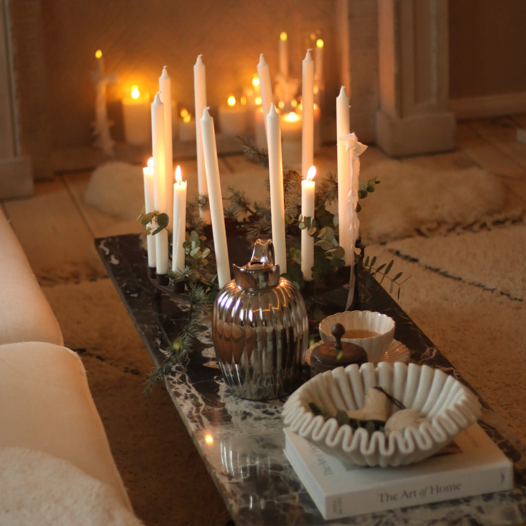 Chandelier décoratif avec bougies blanches sur table en marbre avec bol en céramique et pichet en métal
