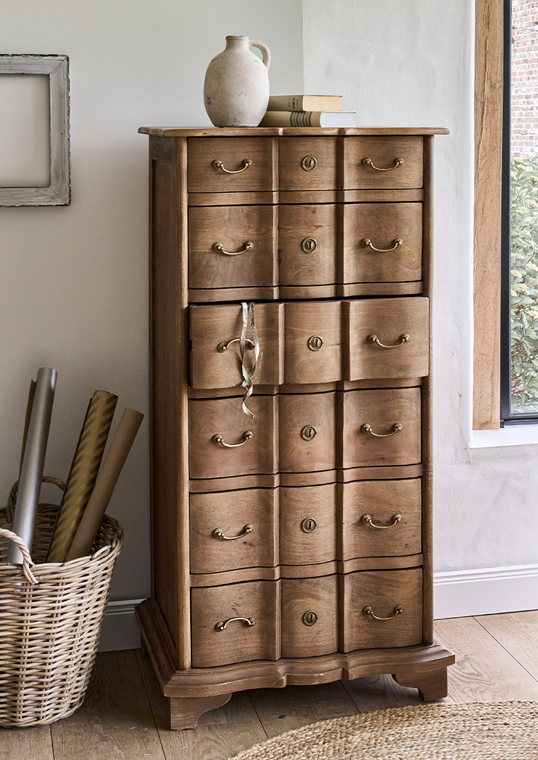 Commode en bois naturel avec six tiroirs et poignées en laiton dans un intérieur lumineux