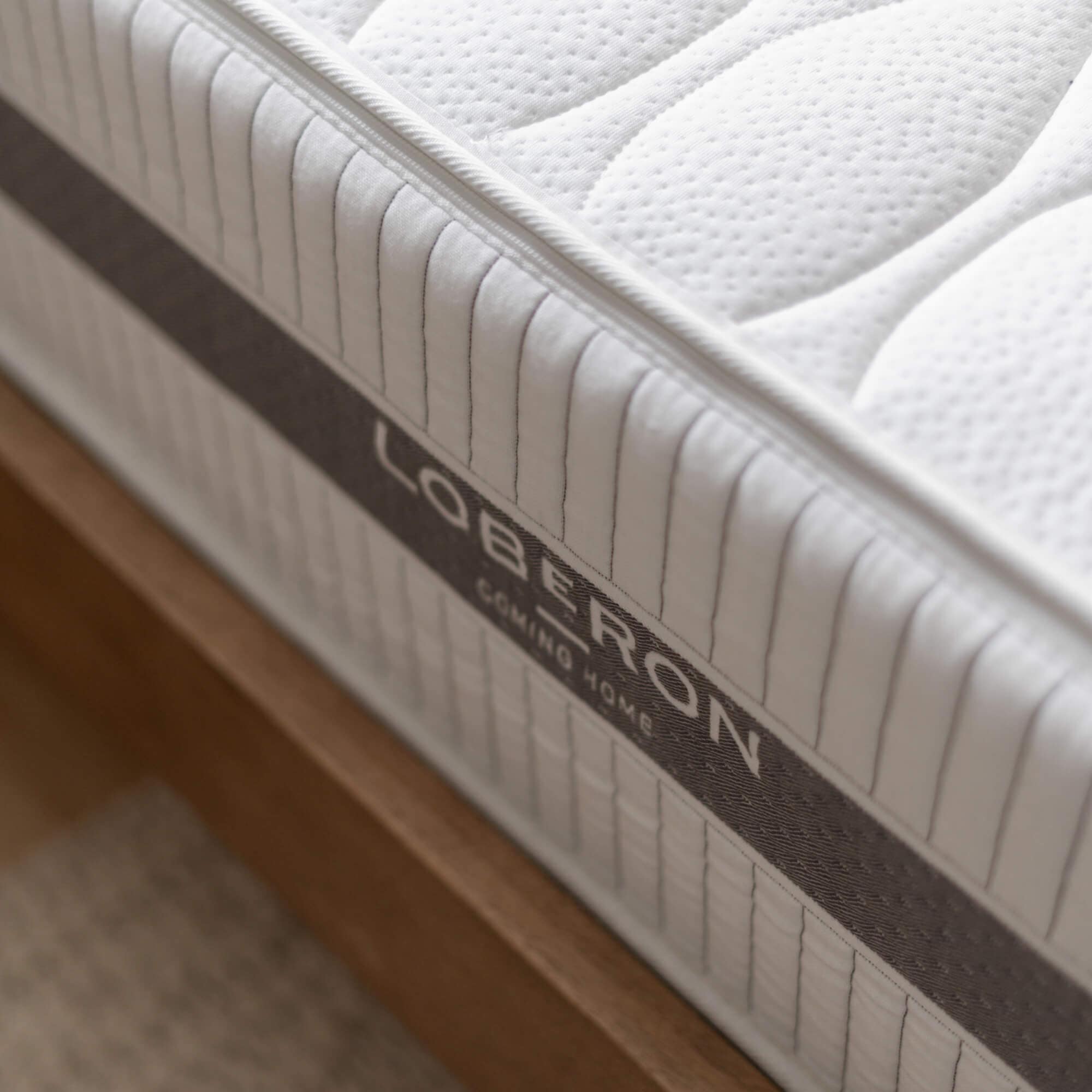 Tissu matelassé blanc de matelas avec bordure grise sur cadre de lit en bois