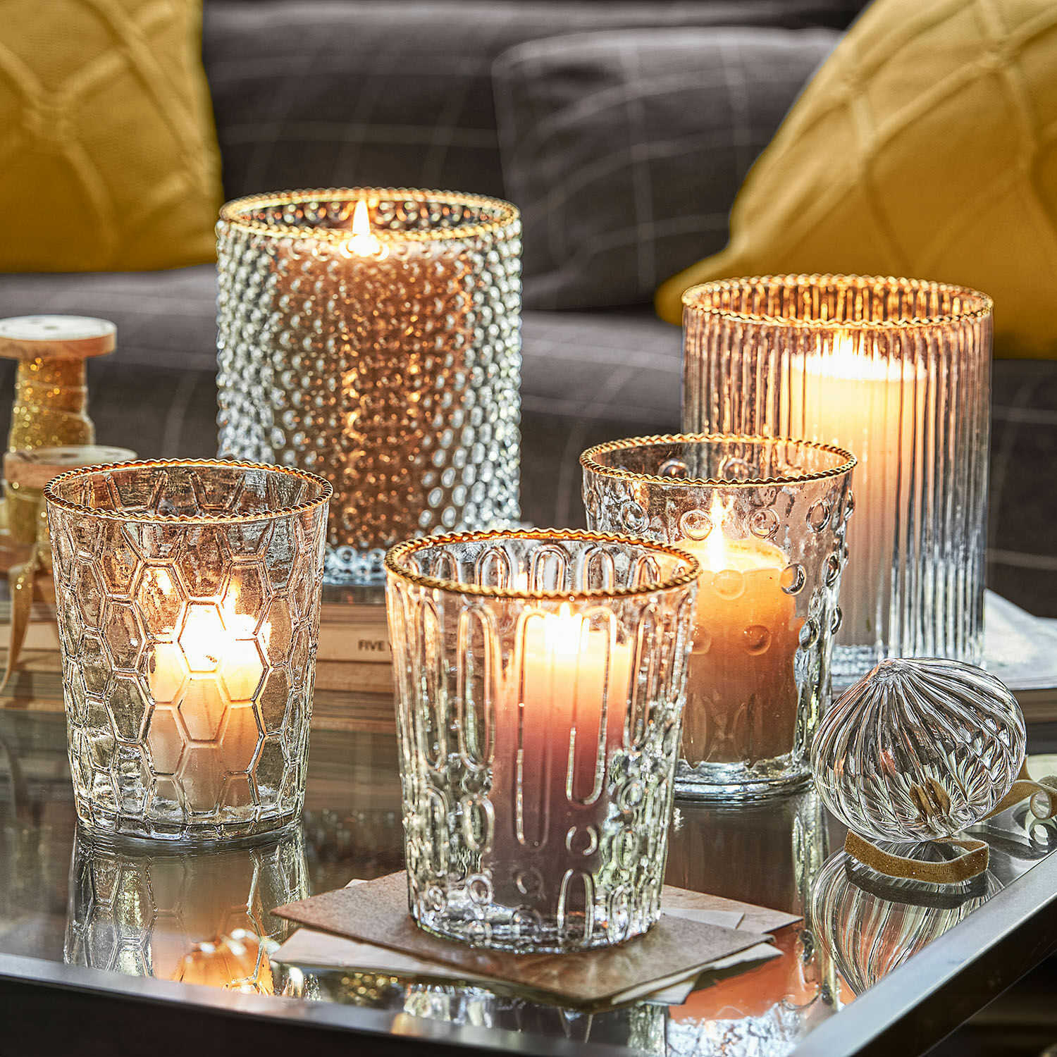 Lot de 5 photophores Rosienne Photophores en verre texturé avec bord doré sur une table en verre dans un salon cosy