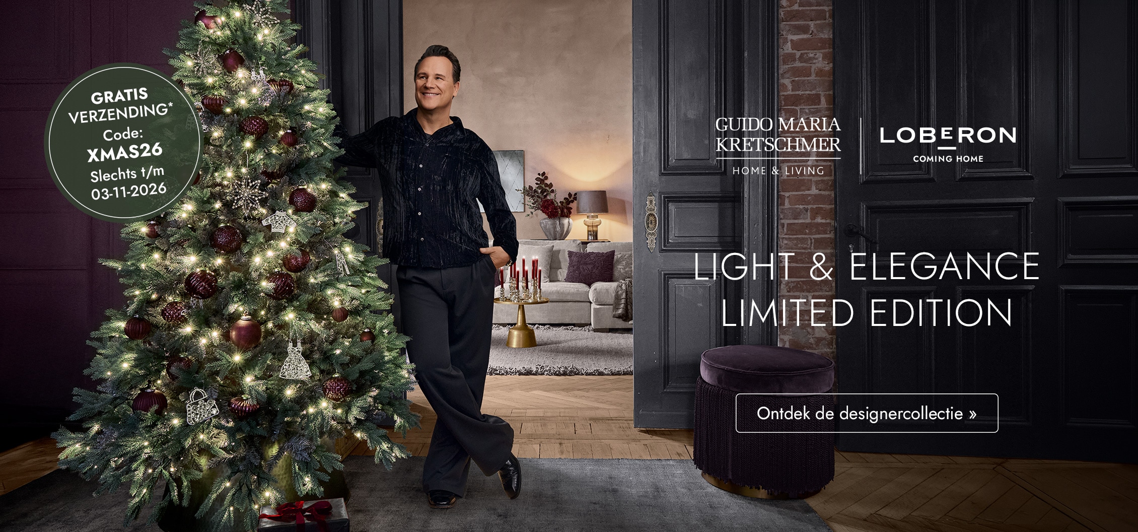 Man naast verlichte kerstboom met bordeauxrode versieringen in een elegante feestelijke kamer