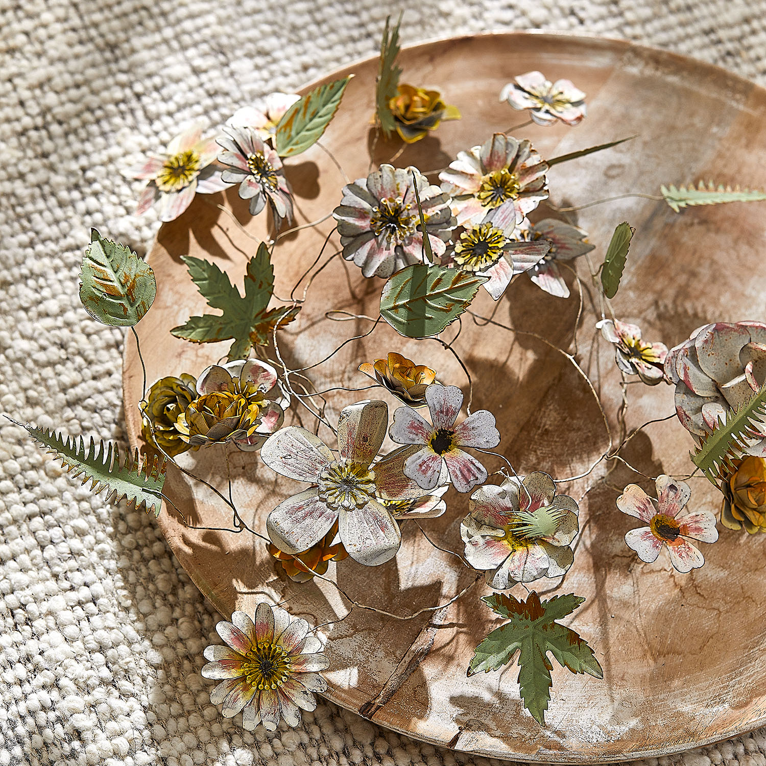 Fleurs et feuilles décoratives en métal aux couleurs pastel sur un plateau en bois, décoration intérieure