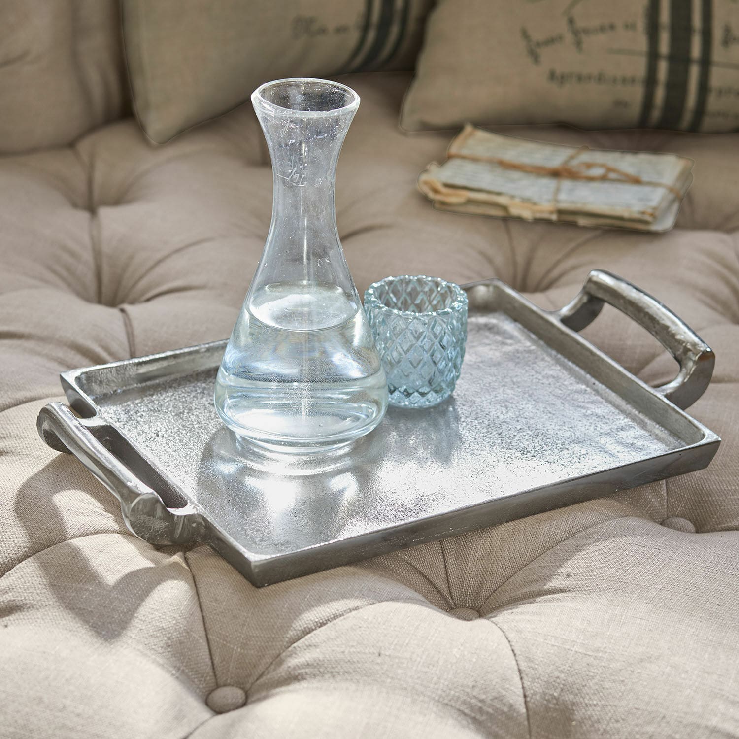 Dienblad Connaire Decoratief zilverkleurig metalen dienblad op beige gewatteerde stof met karaf en glas