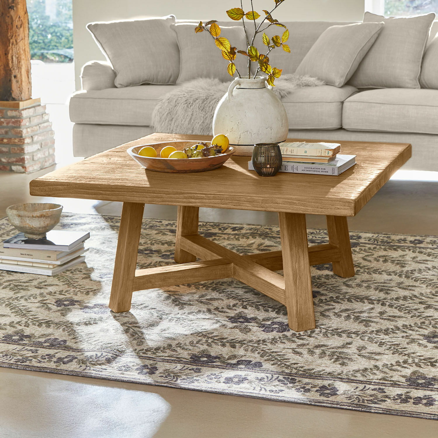 Table basse Eldonbury Table basse carrée en chêne naturel posée sur un tapis à motifs dans un salon lumineux