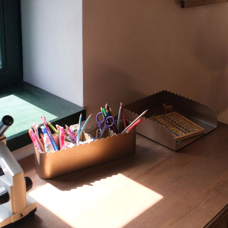 Boîtes de rangement en métal brun avec bords ondulés, contenant des fournitures de bureau et un livre