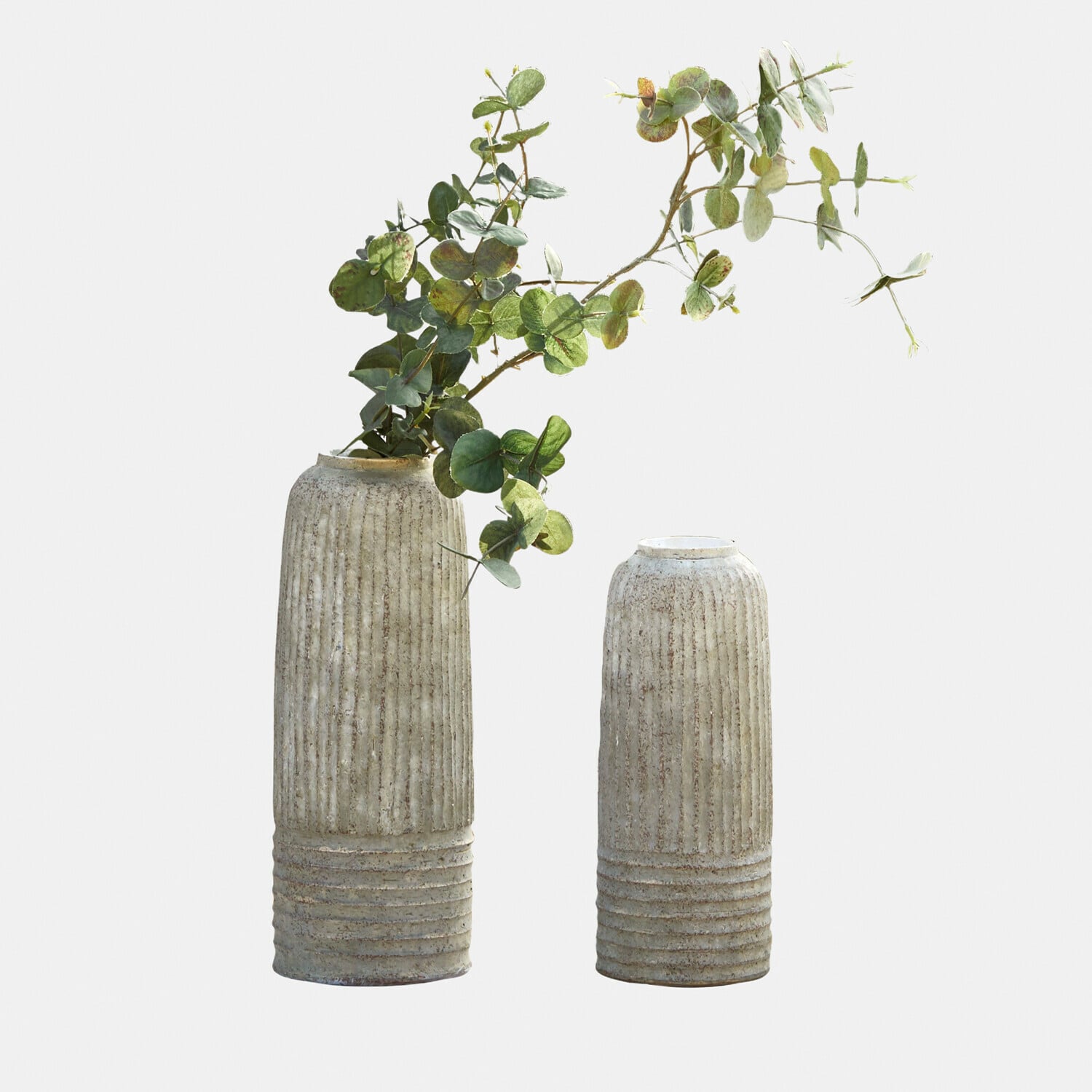Deux vases en céramique beige texturée, l'un avec des feuilles d'eucalyptus vertes, décoration intérieure moderne
