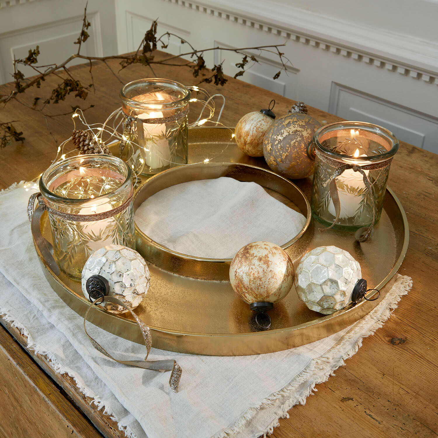Plateau à bougies Velarosas Plateau en métal doré avec trois photophores en verre et boules décoratives sur table en bois