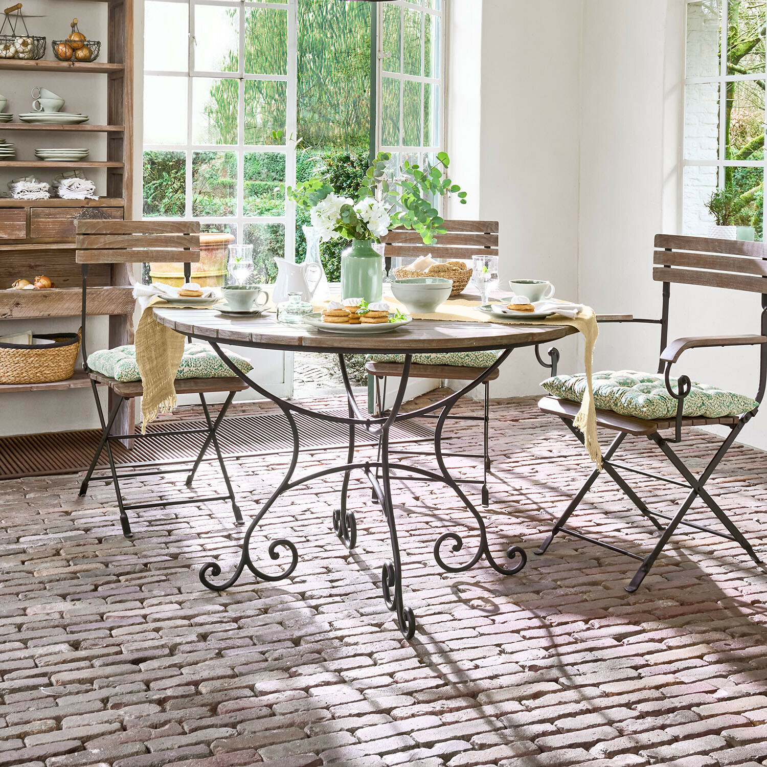 Table ronde en bois avec pieds en métal dans une salle à manger rustique avec chaises et décoration florale