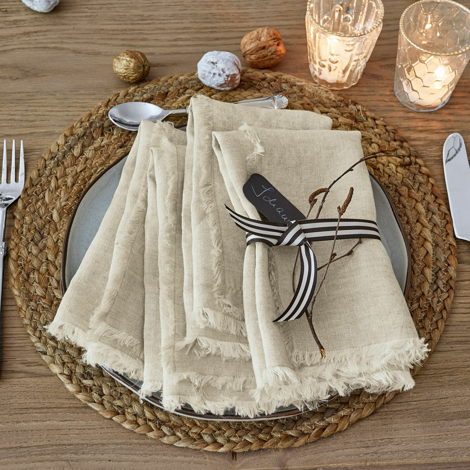 Servet set van 4 Largo Beige linnen servetten met franjes op een gevlochten houten placemat met kerstdecoratie