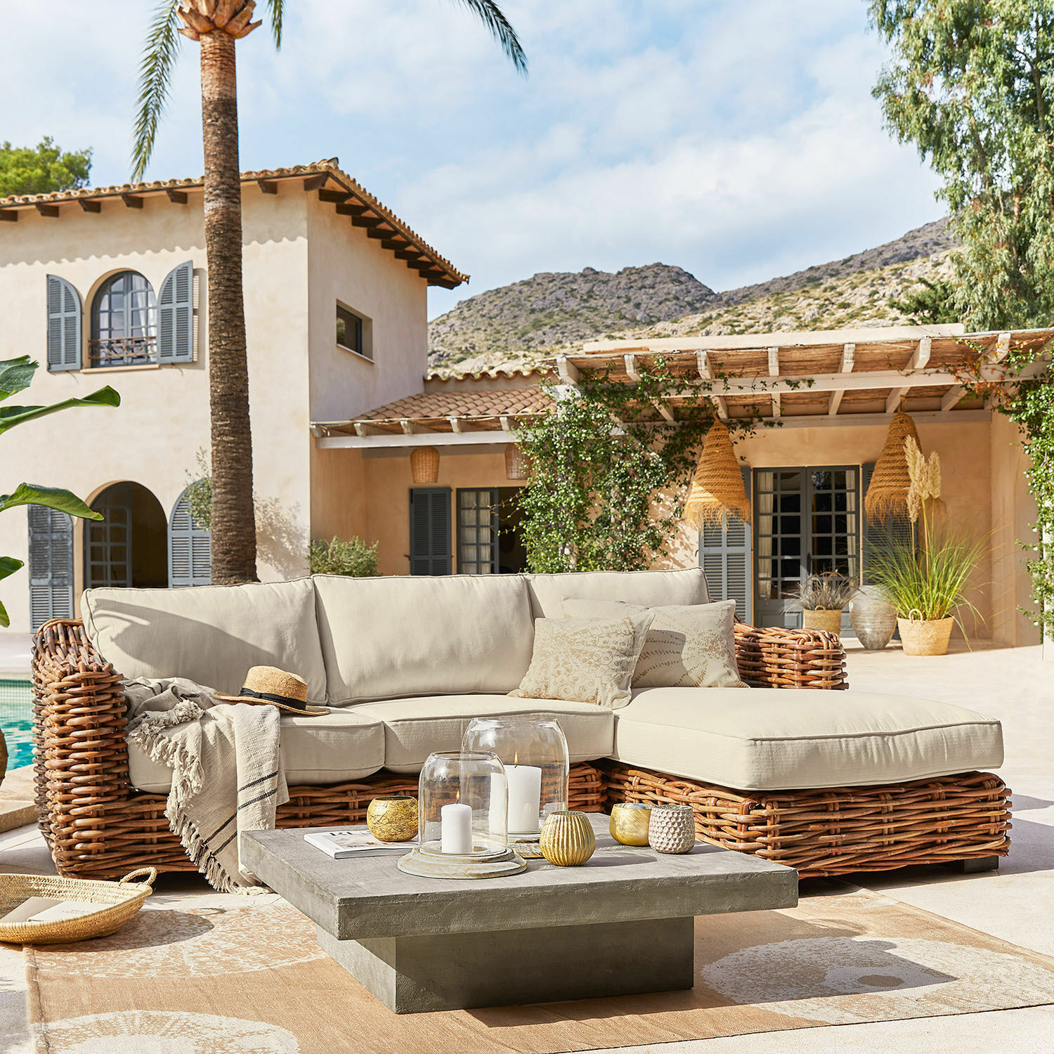 Rattan loungeset met beige kussens op terras met betonnen salontafel