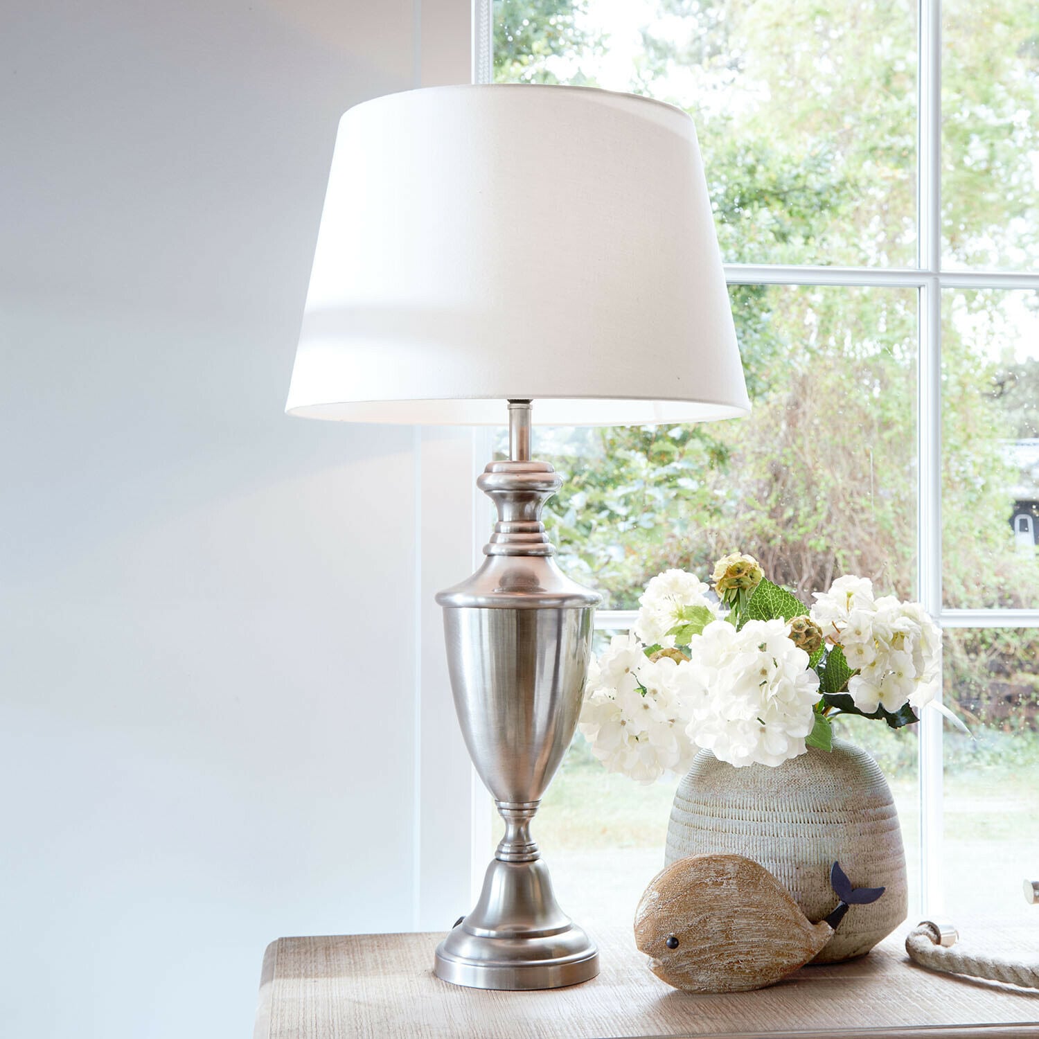 Lampe à poser Montalure Lampe de table avec base en métal et abat-jour blanc sur une table en bois avec décoration florale