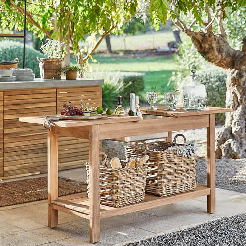 Tuin tafel van natuurlijk hout met rieten manden en serveeraccessoires op zonnig terras