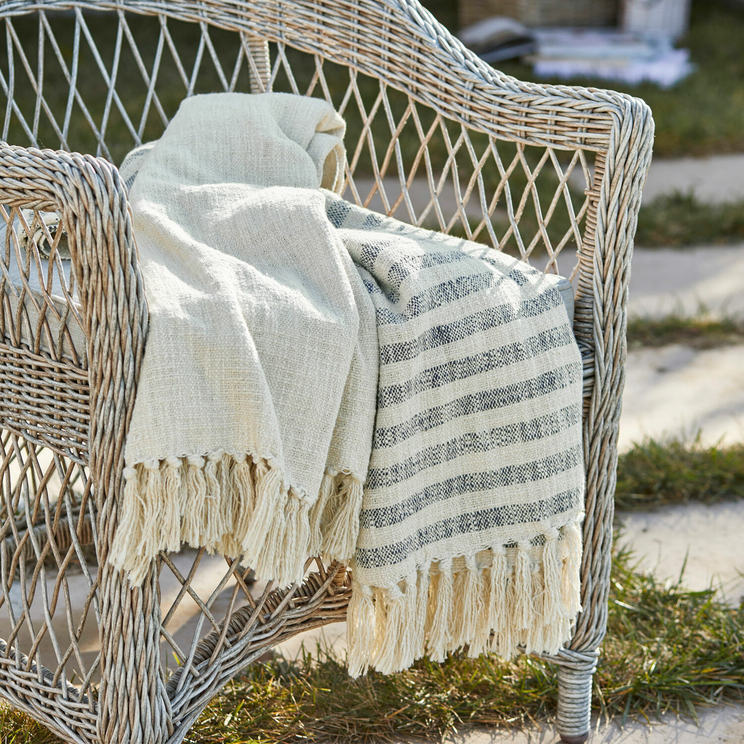 Plaid Marpent Beige katoenen deken met franjes op een rotan stoel in de tuin, decoratie en comfort