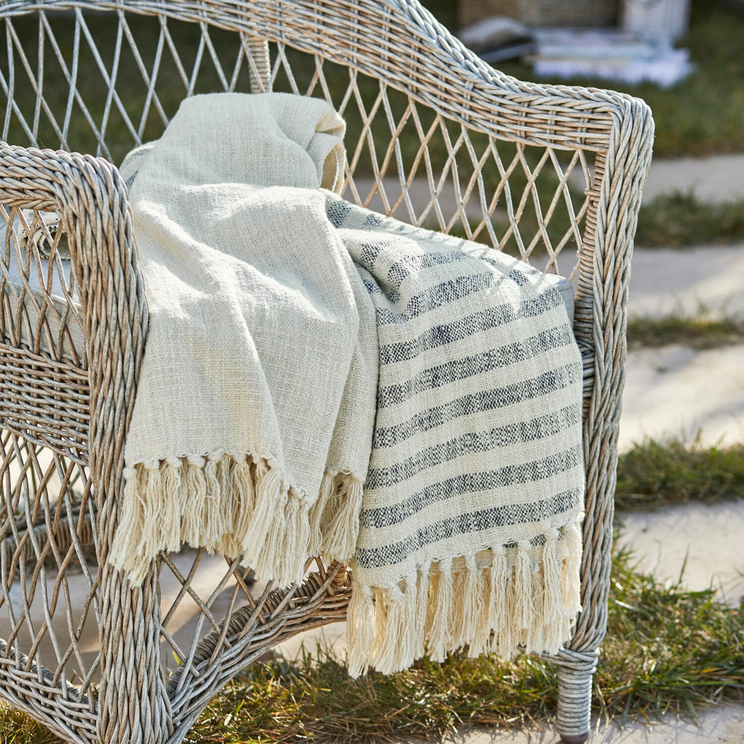 Plaid Marpent Plaid beige en coton avec franges sur fauteuil en osier, décoration extérieure confortable